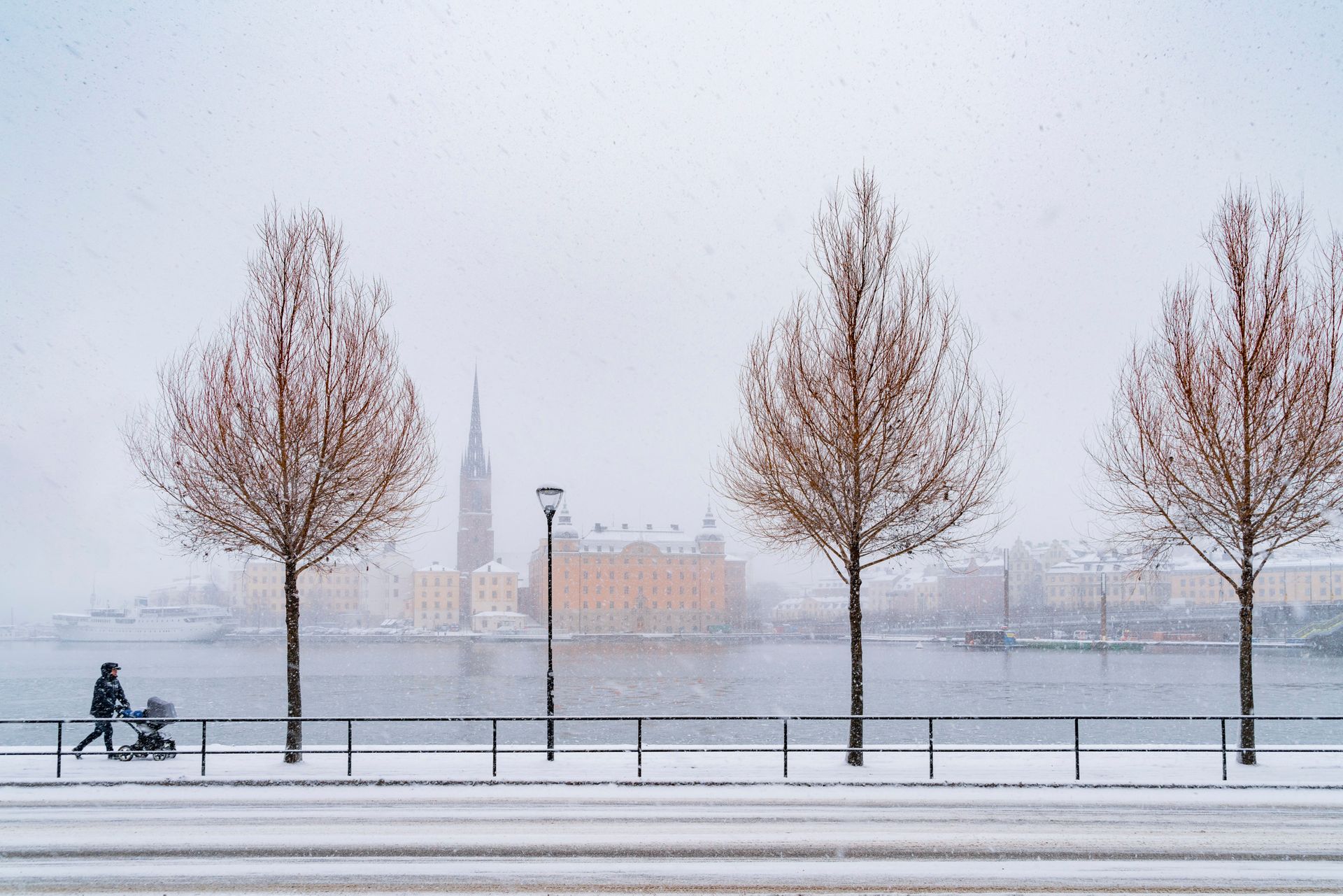 A man walking with a pram in a snowy city.