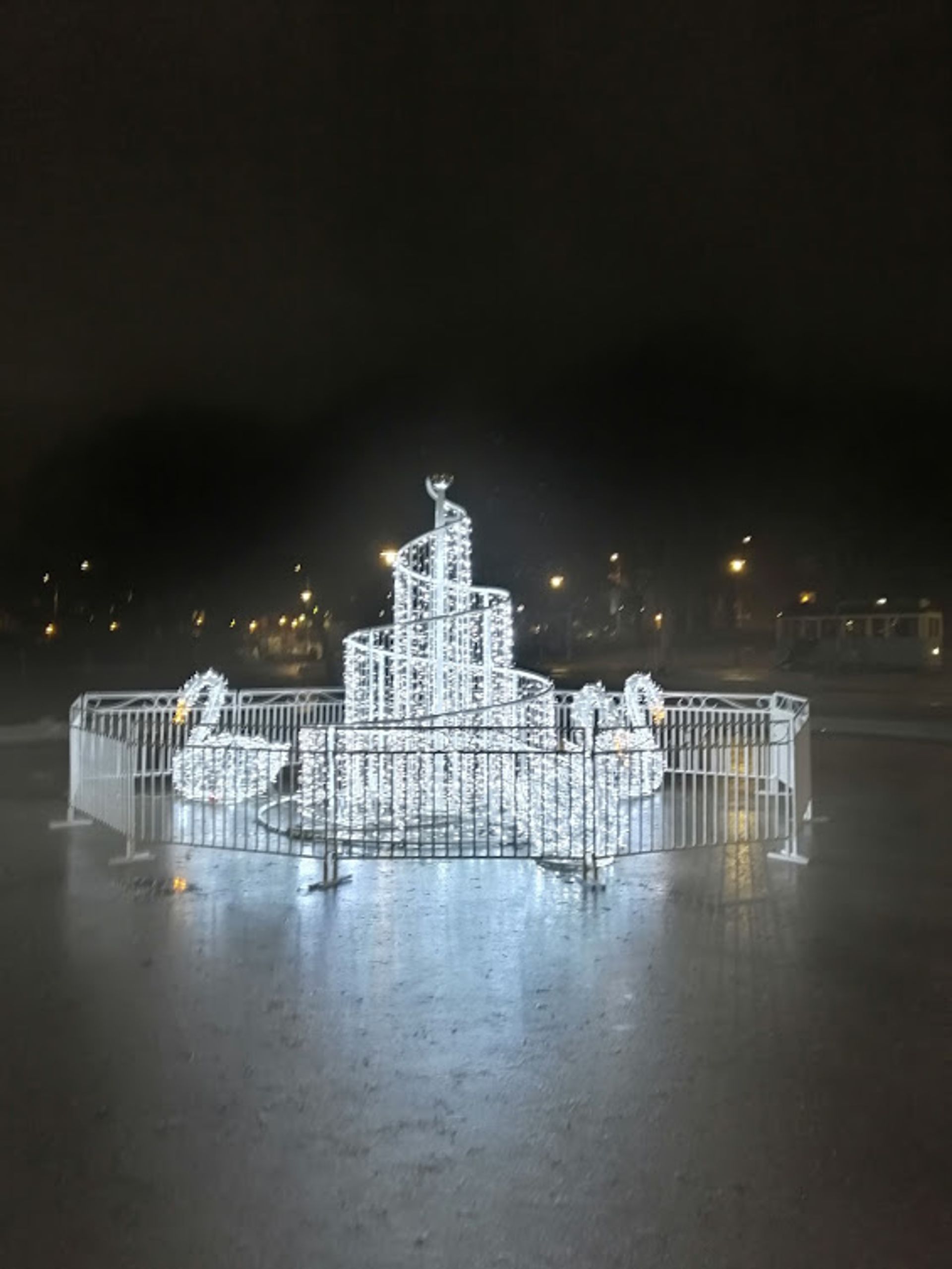 A light sculpture of swans around a spiral of fairy lights