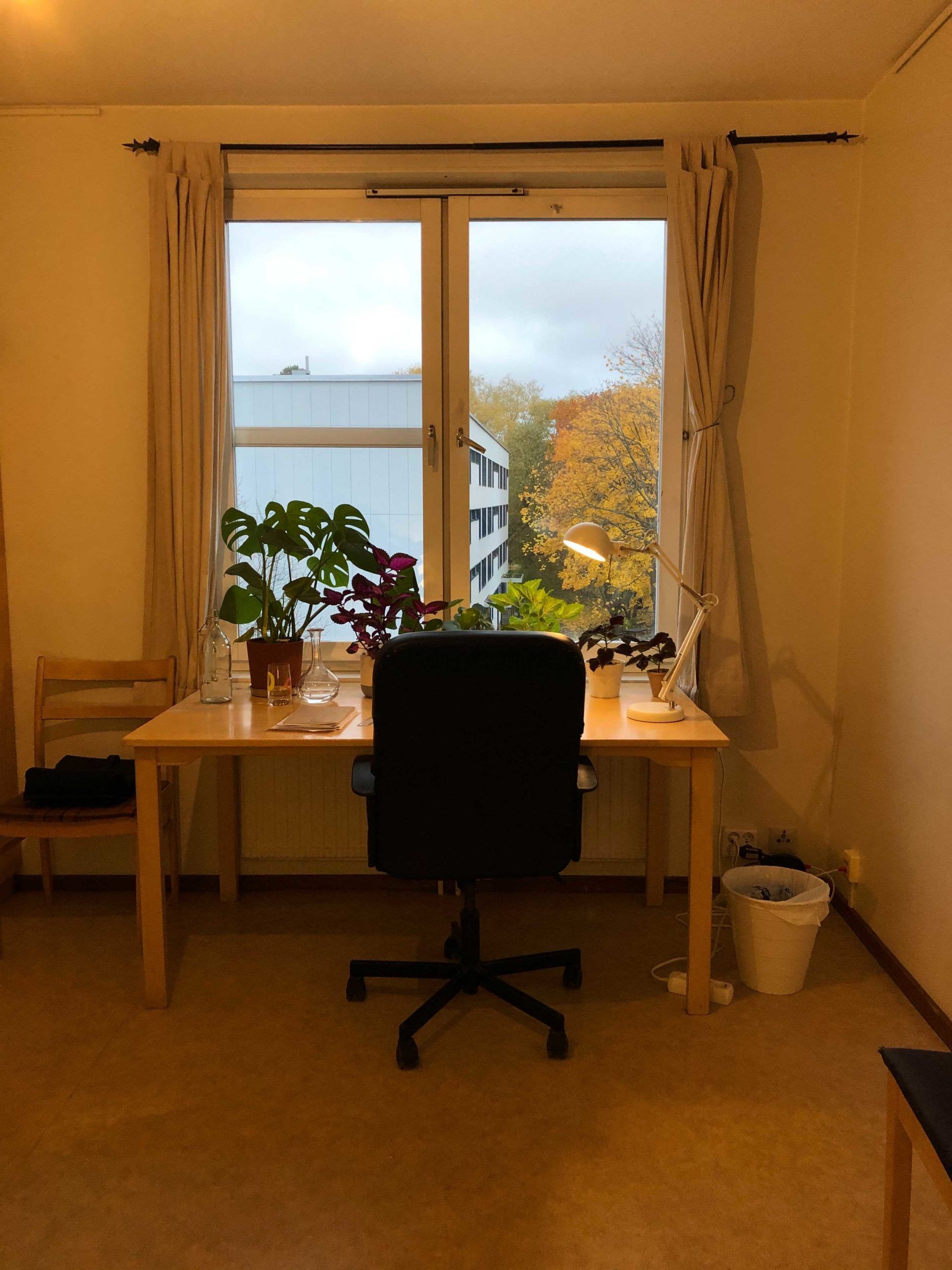 Desk and chair sit in front of large window with light shining through