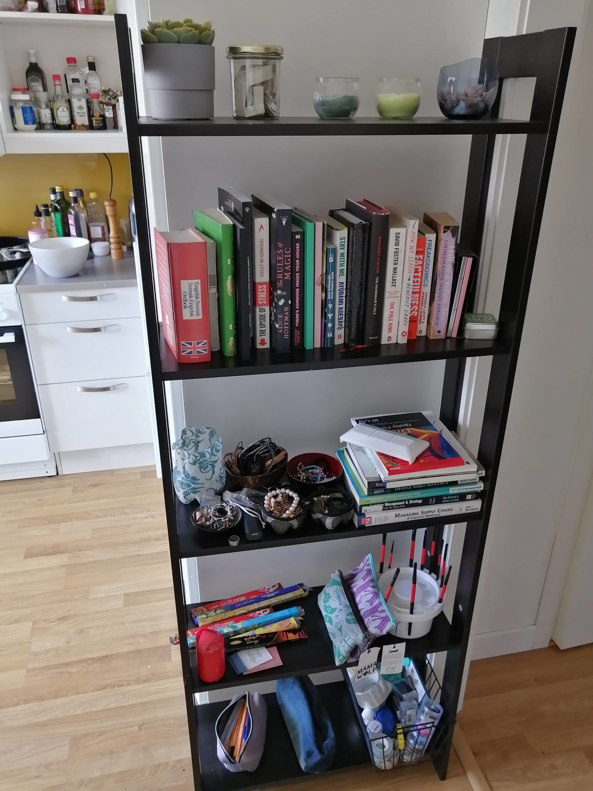 A book shelf with books and candle holders