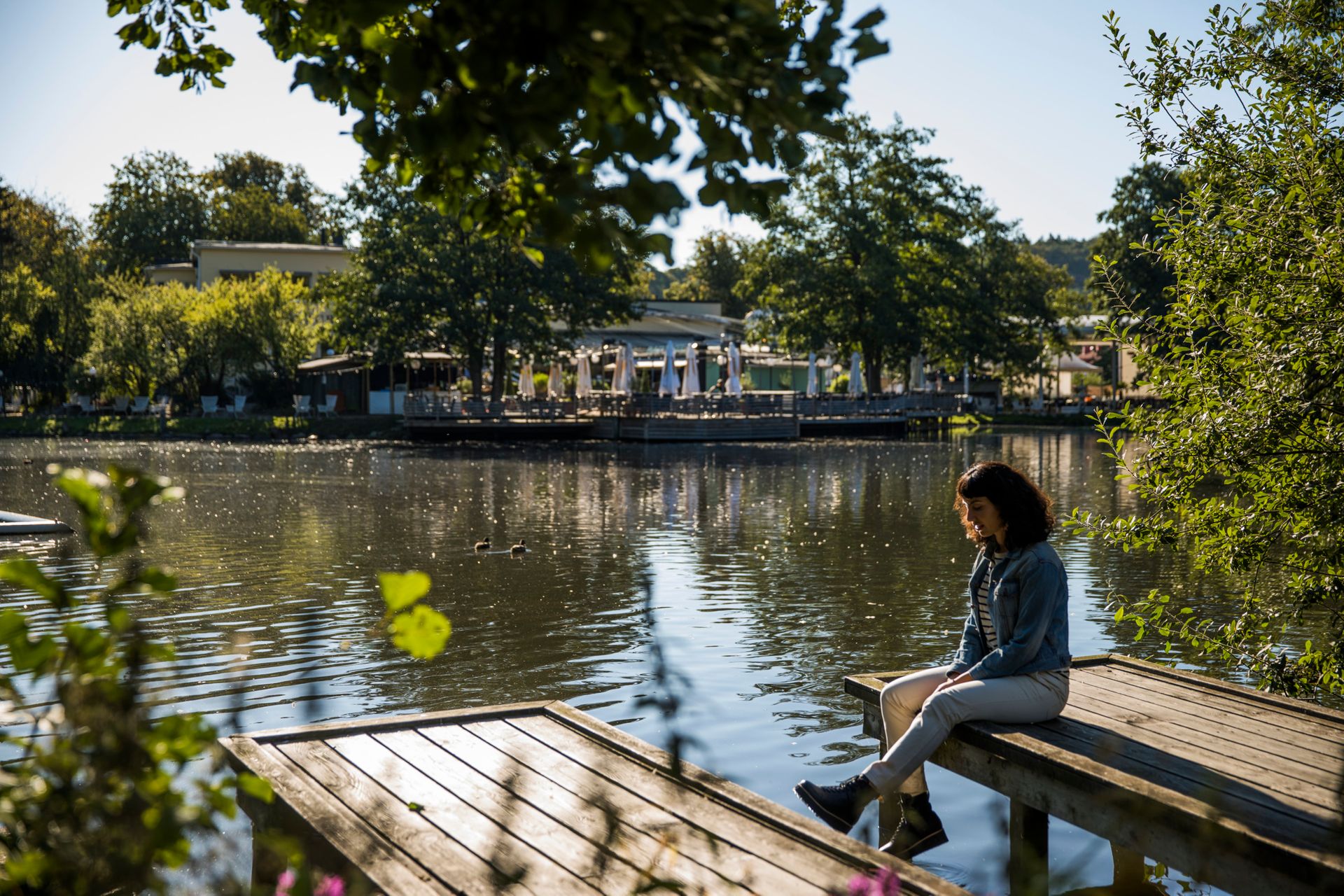 A girl sitting on a deck above water, in one of the biggest parks of Gothenburg