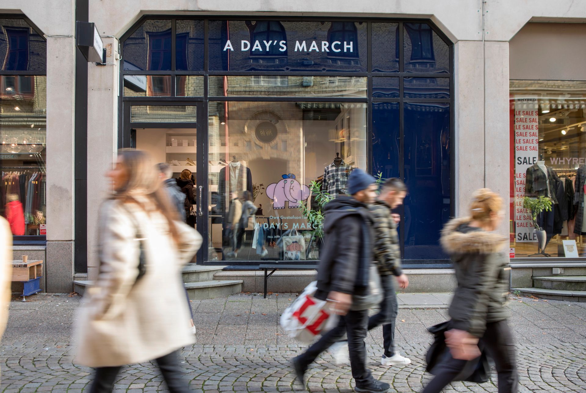 Several people seen blurry walking on a pedestrian shopping street.