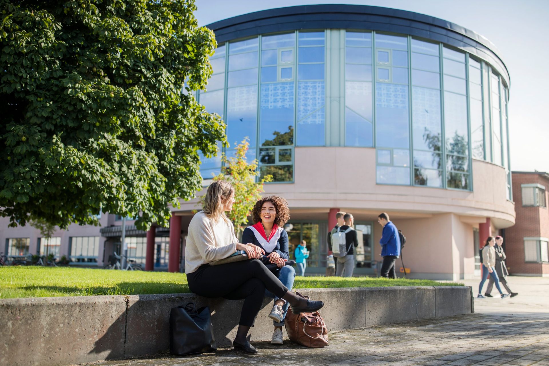 Two students sitting and talking outside the university building of Örebro University.