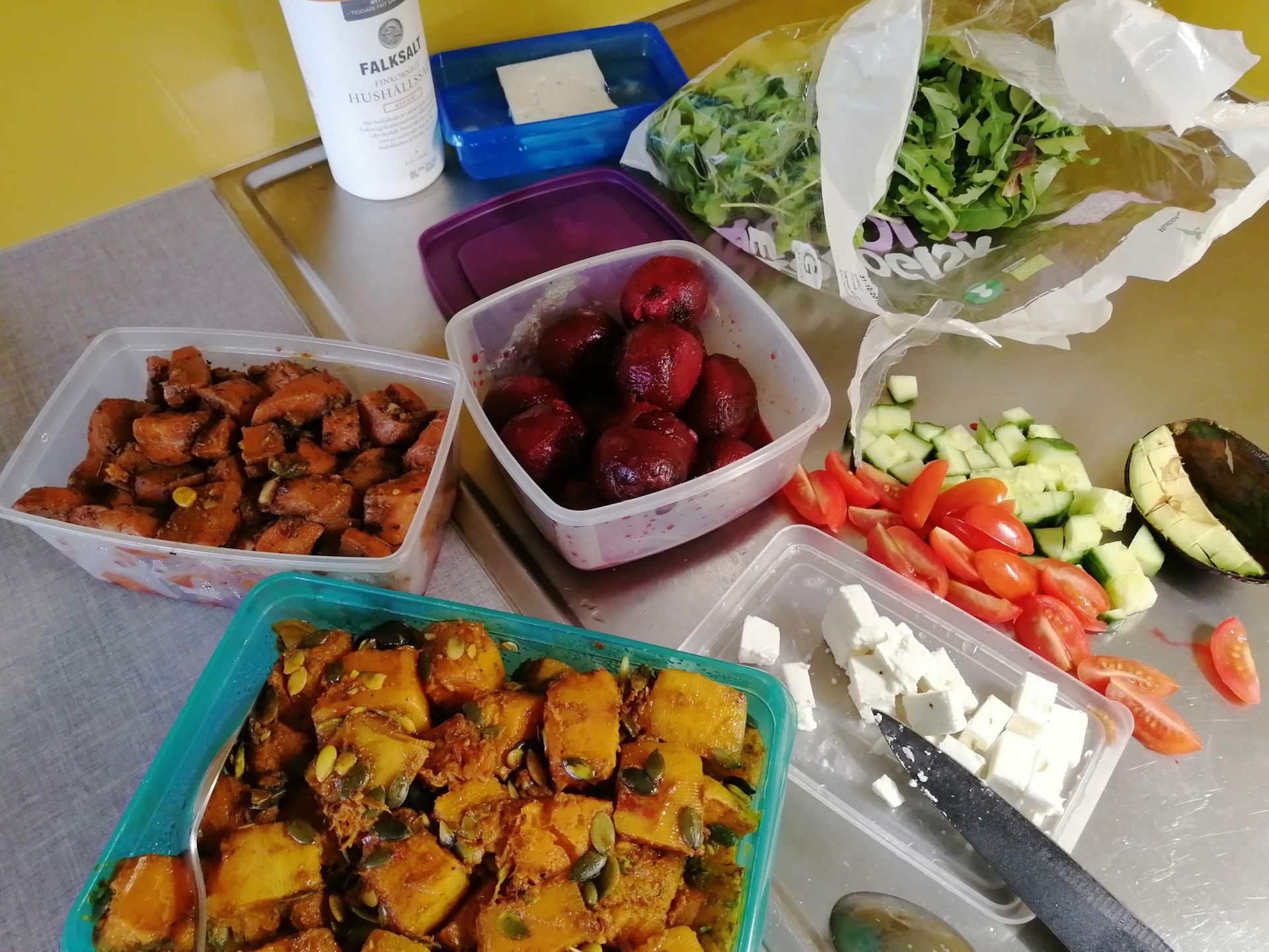 An assortment of cooked and raw vegetables on a kitchen counter, prepared to make a salad