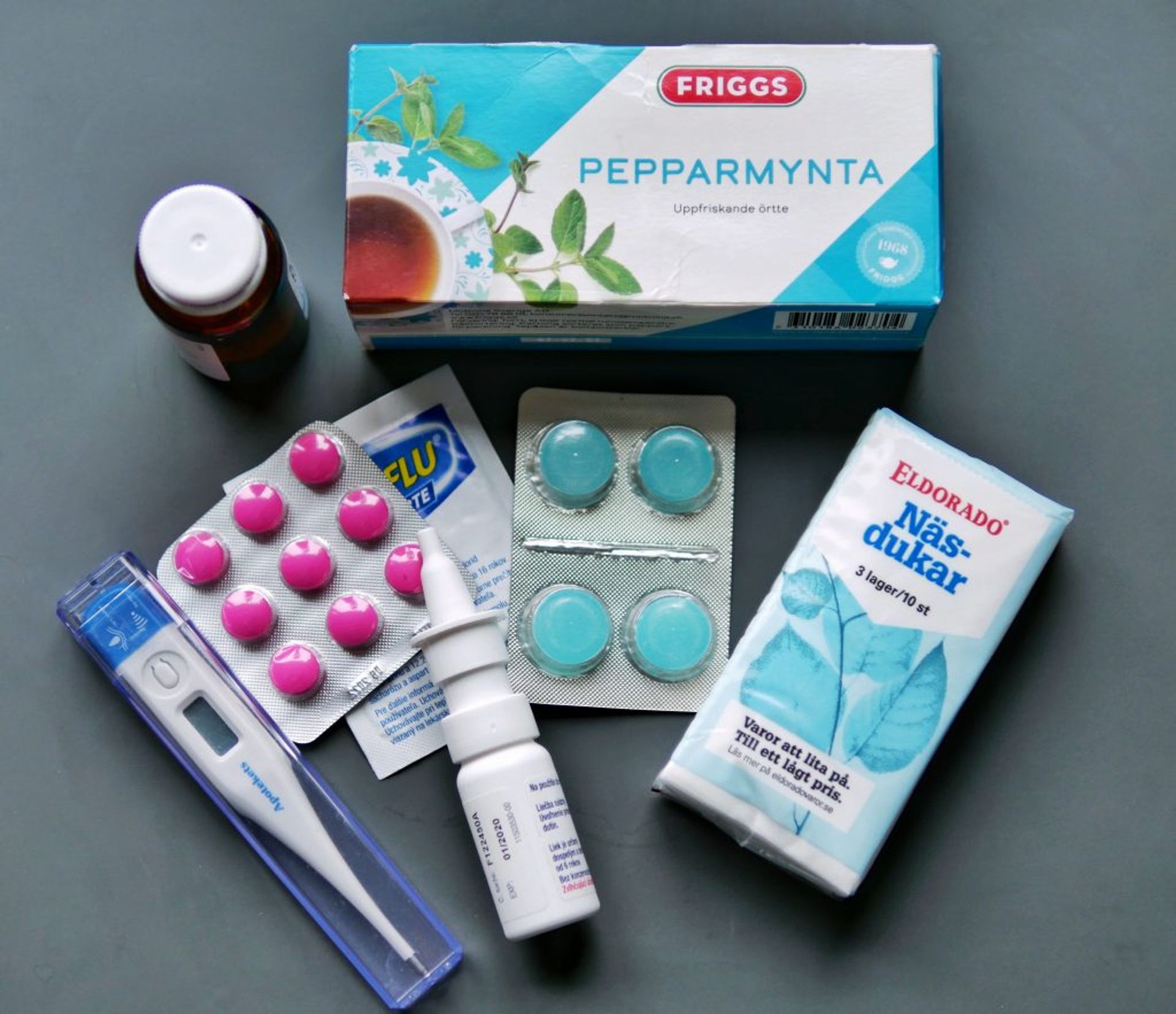 Flu kit containing tea, tissues, thermometer, nasal spray and medications.