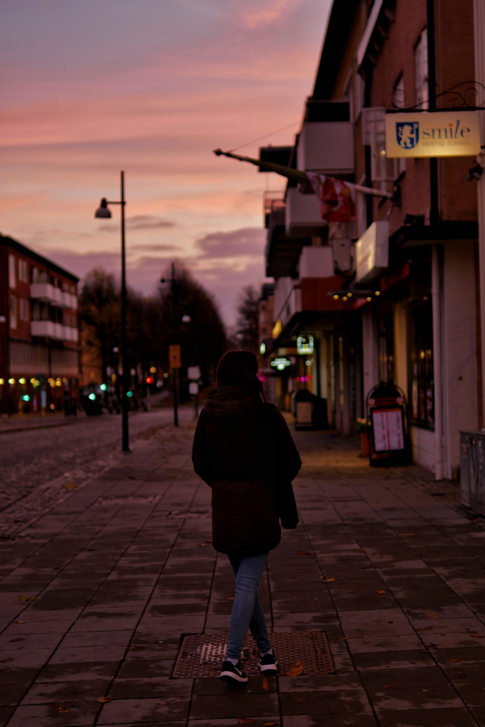 A girl walking on a street at sunset.
