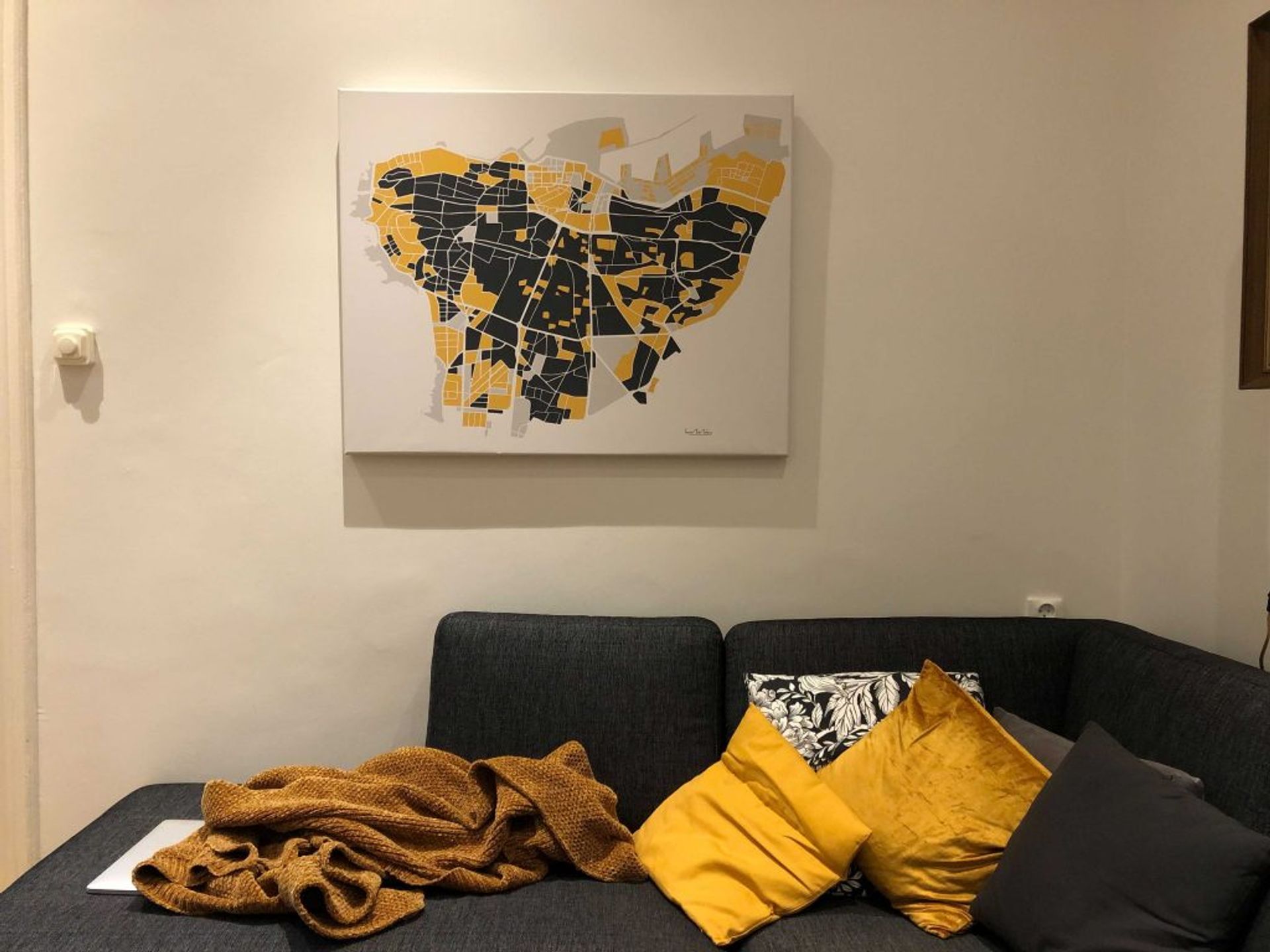 Picture showing a sofa and a canvas on the wall. The canva contains an illustration of Beirut.