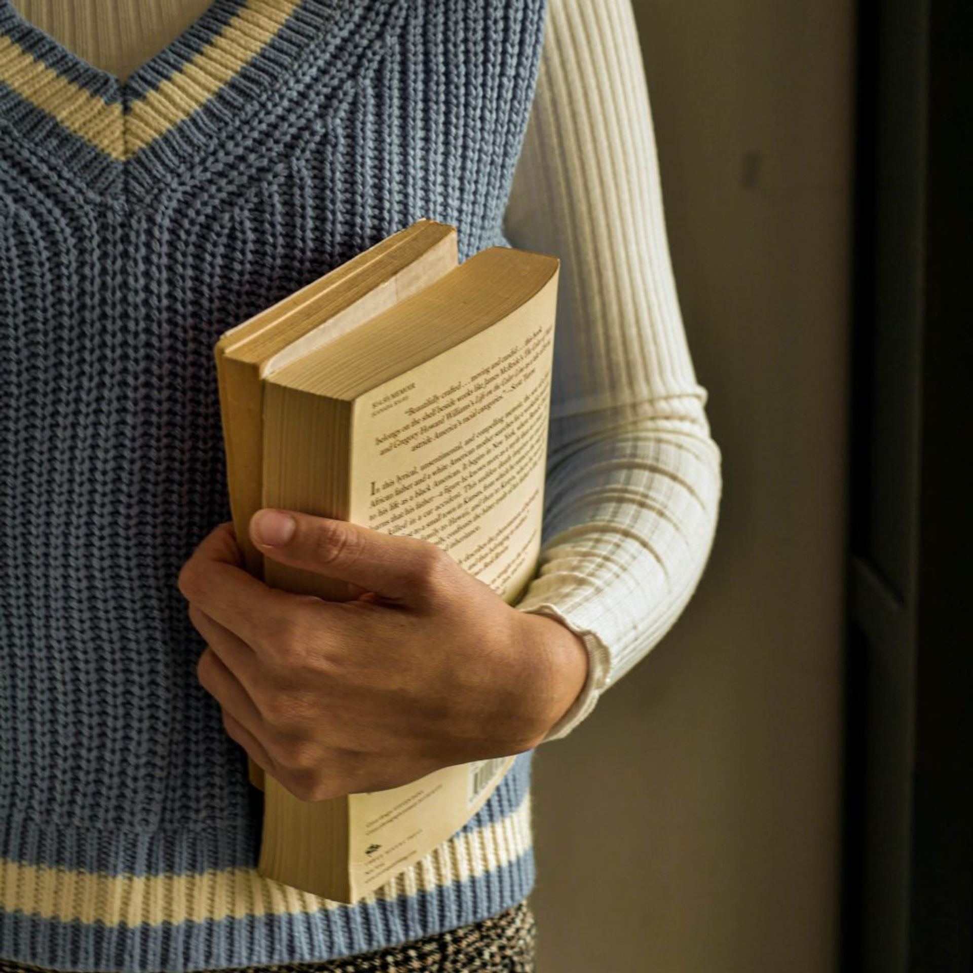 A person holding two books in the left hand. 