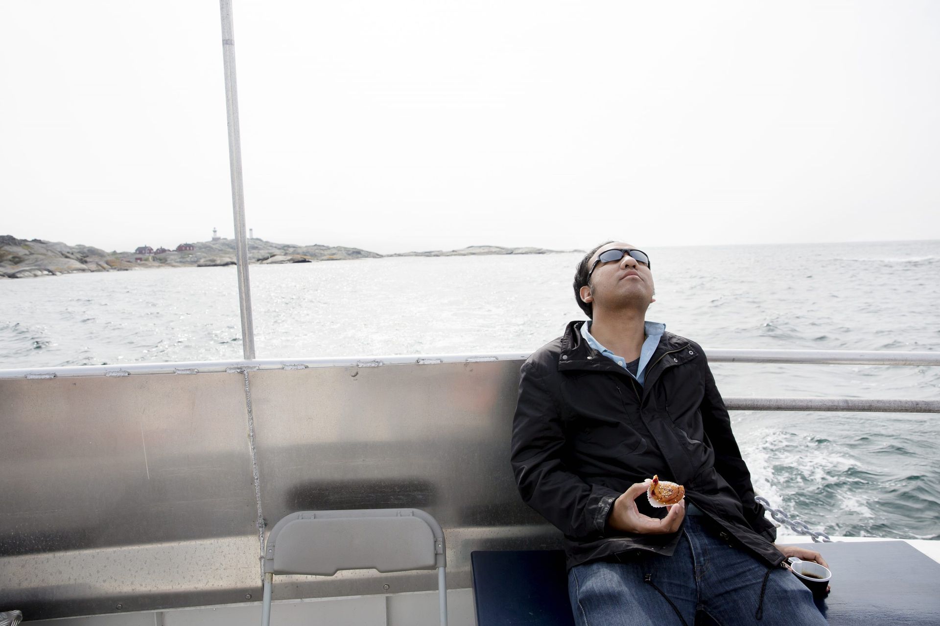 A man relaxing on a bench eating cinnamon roll