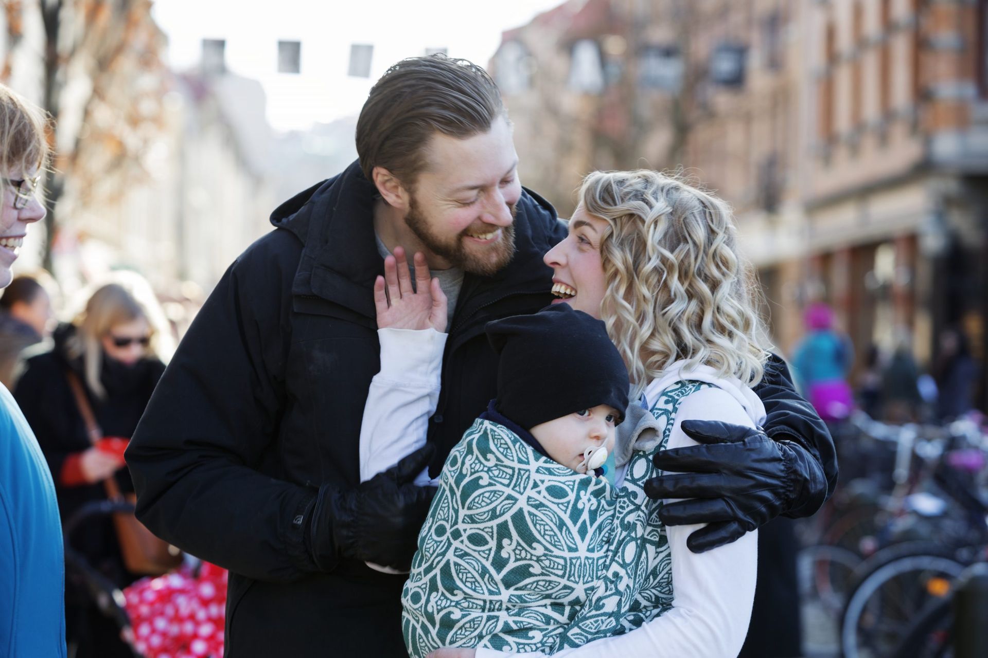 A happy couple laughing with the woman carrying a baby