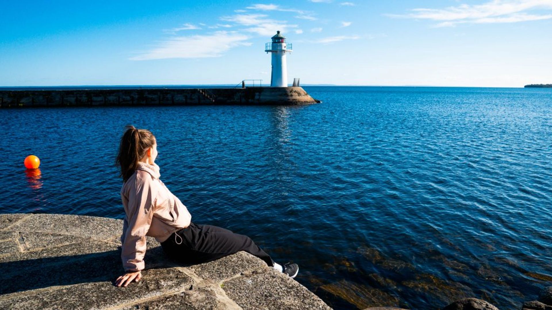 A girl sitting by a blue lake in summer. 