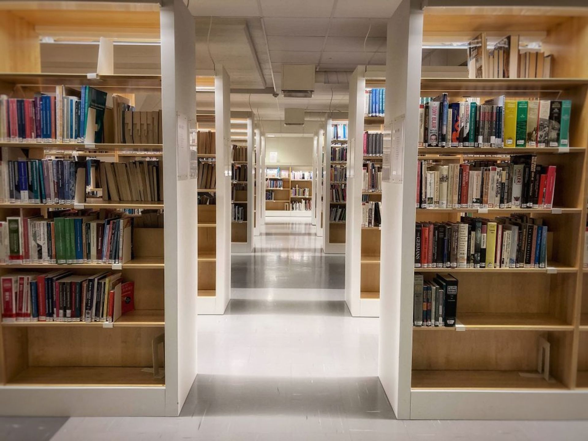 A corridor in the library showing many shelves with books. 