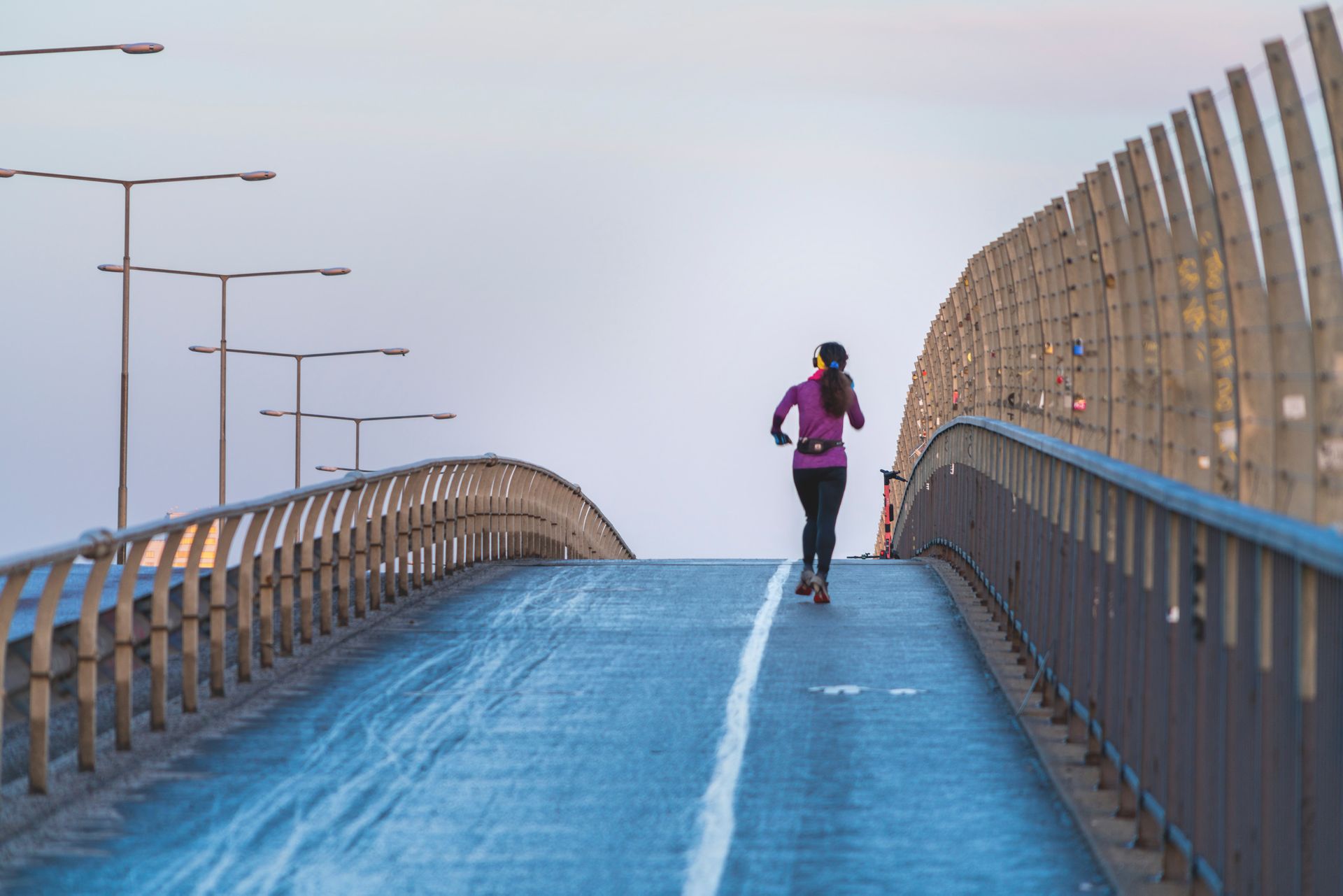 A woman jogs alone on a bridge.