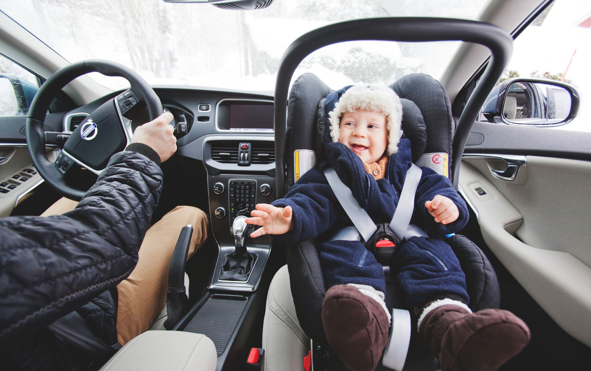 A smiling baby in the car seat with safety belt on. 