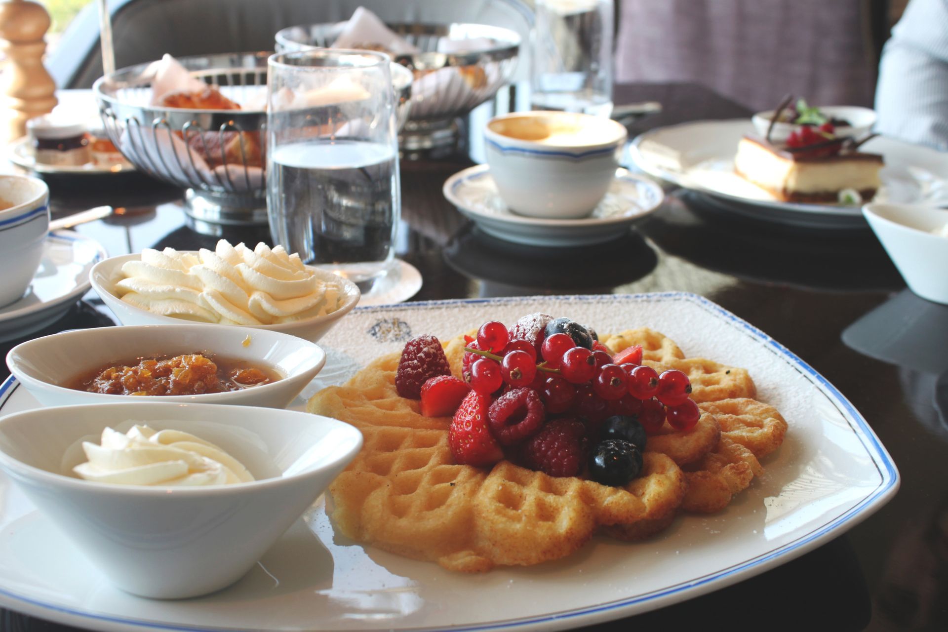 A table set with waffles, dessert and coffee.