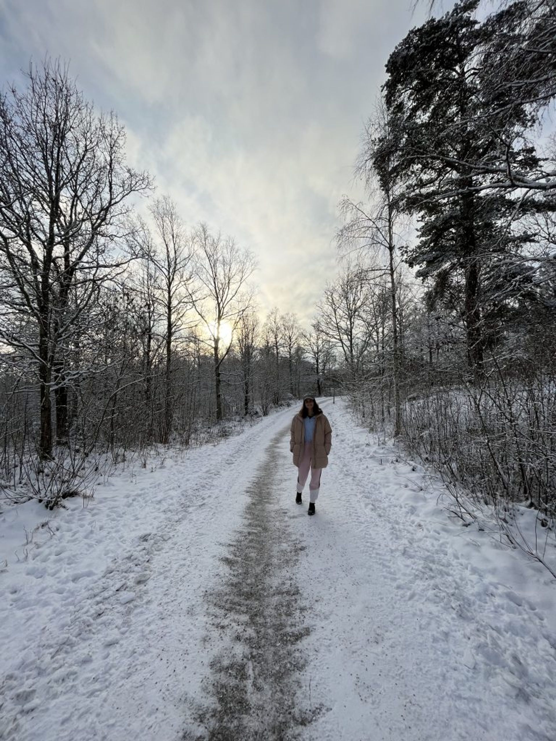 A girl walking on a white snowy path in a forest in winter. 