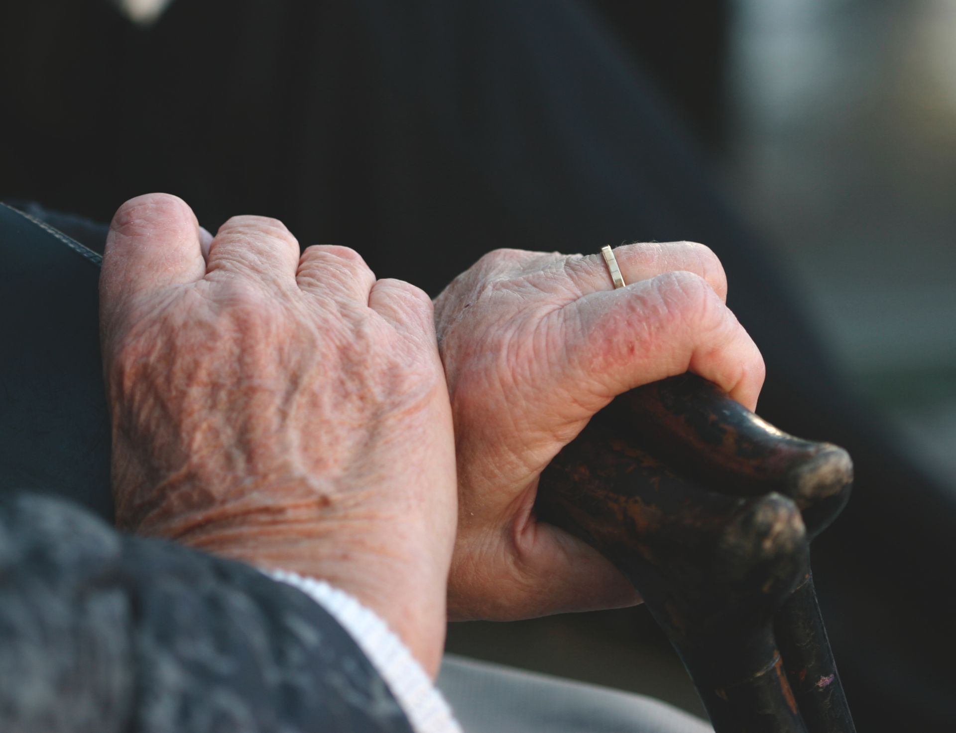 Two hand of elderly person holding a stick.