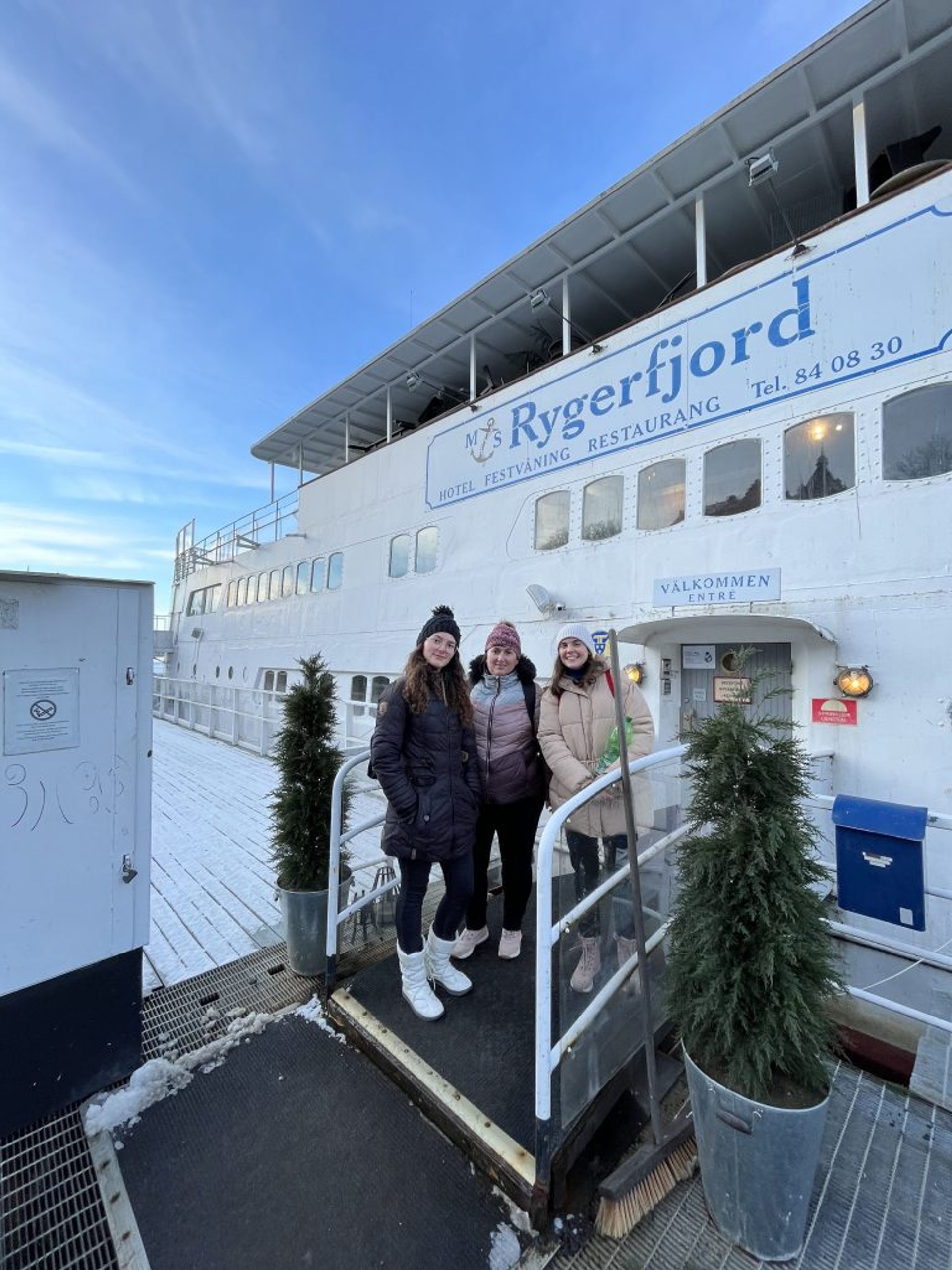 Three girls posing in front of a hotel on a boat.