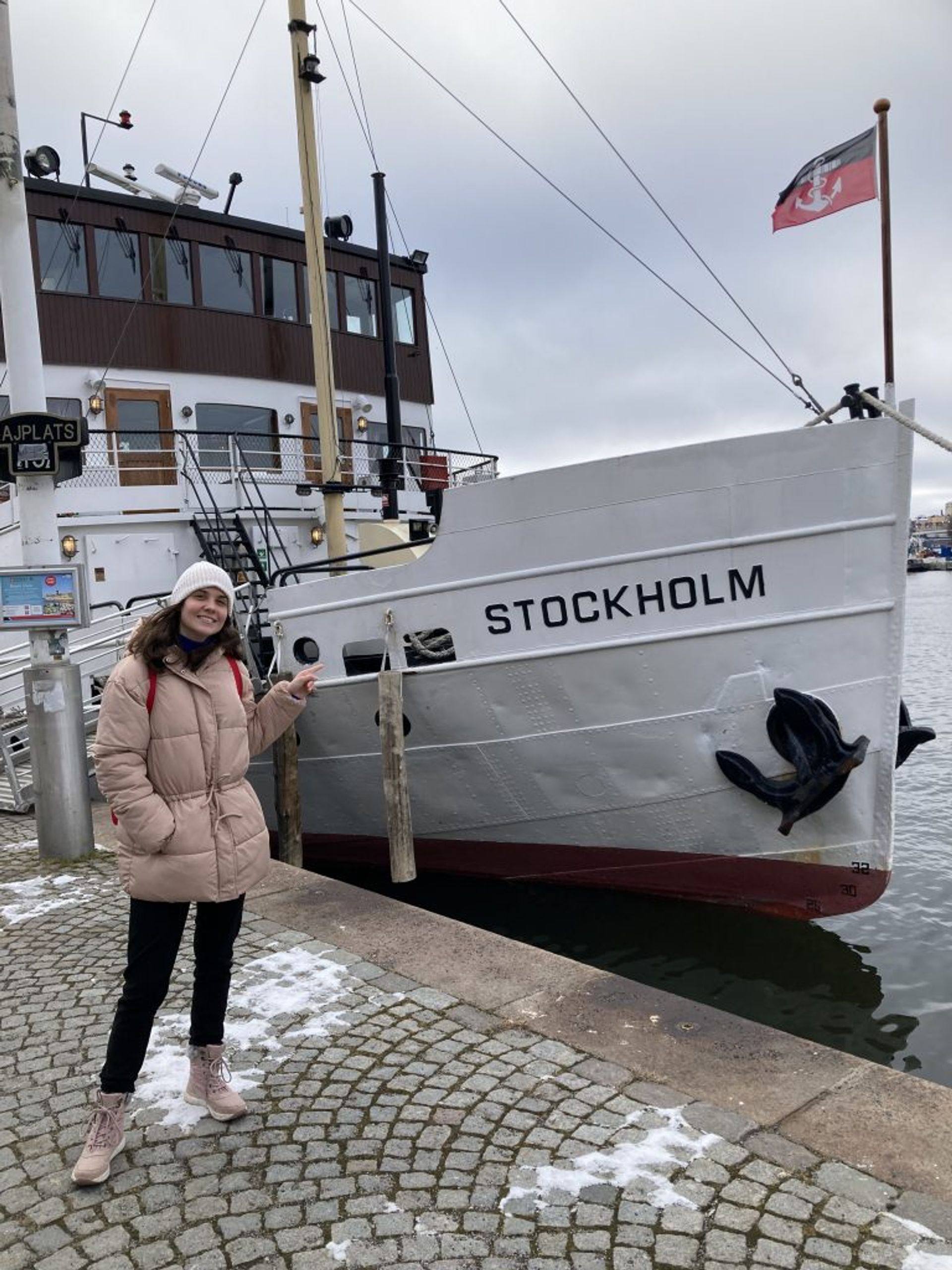 A girl posing next to a boat.