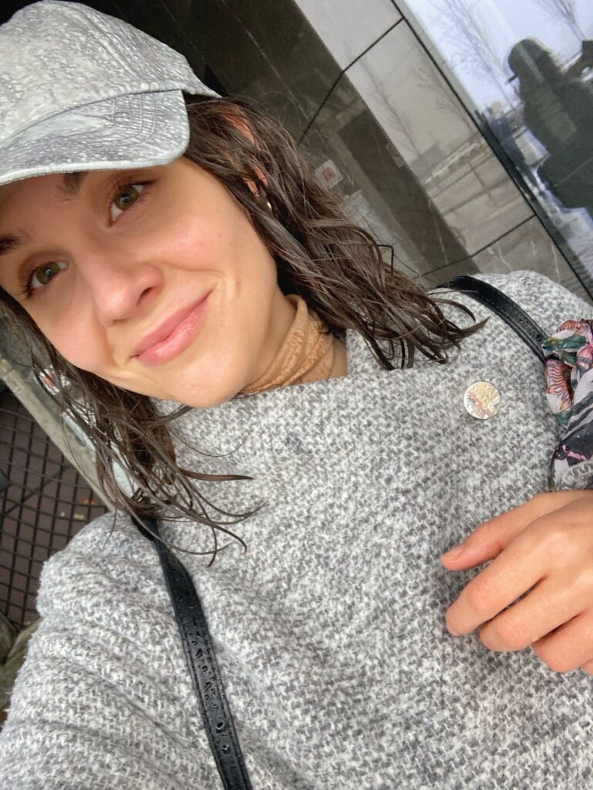 A girl with wet hair and coat holding a broken umbrella. 