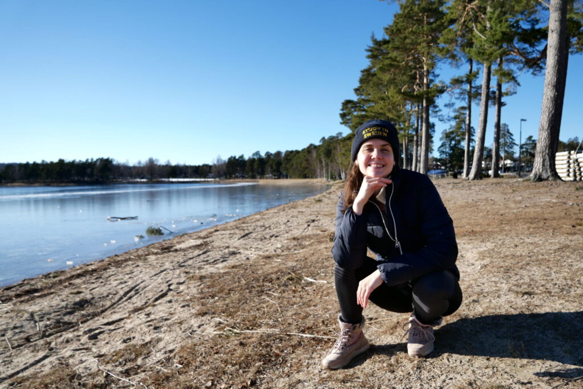 A girl smiling next to a lake. 