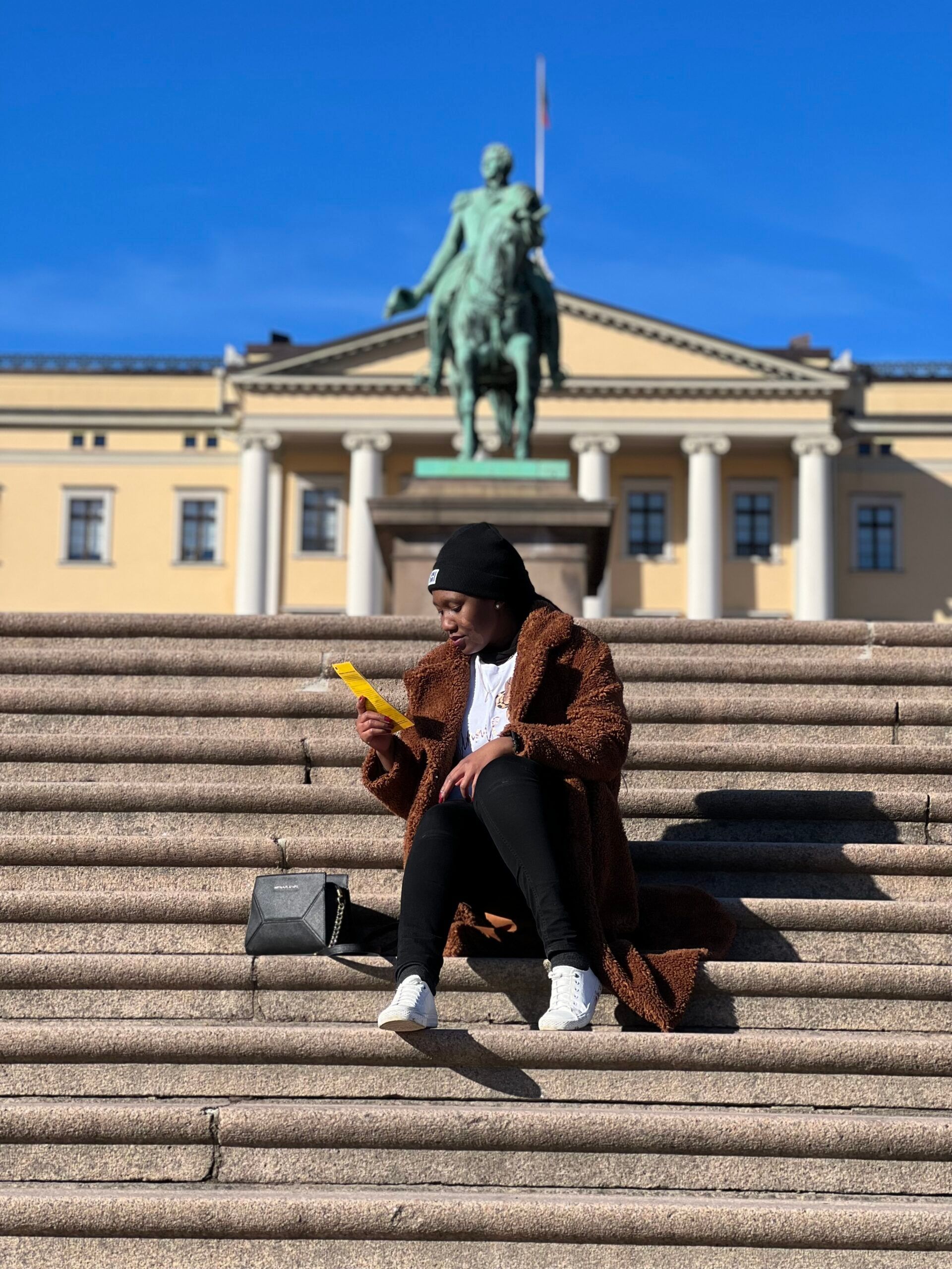 Digital ambassador Nozinhle sitting by the stairs of the Norwegian Royal Palace
