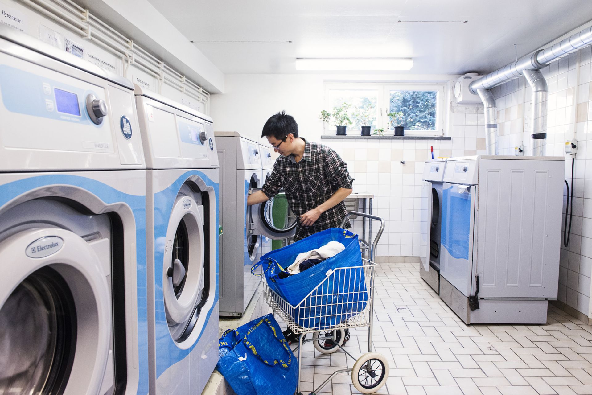 A guy doing laundry in a shared laundry facility.