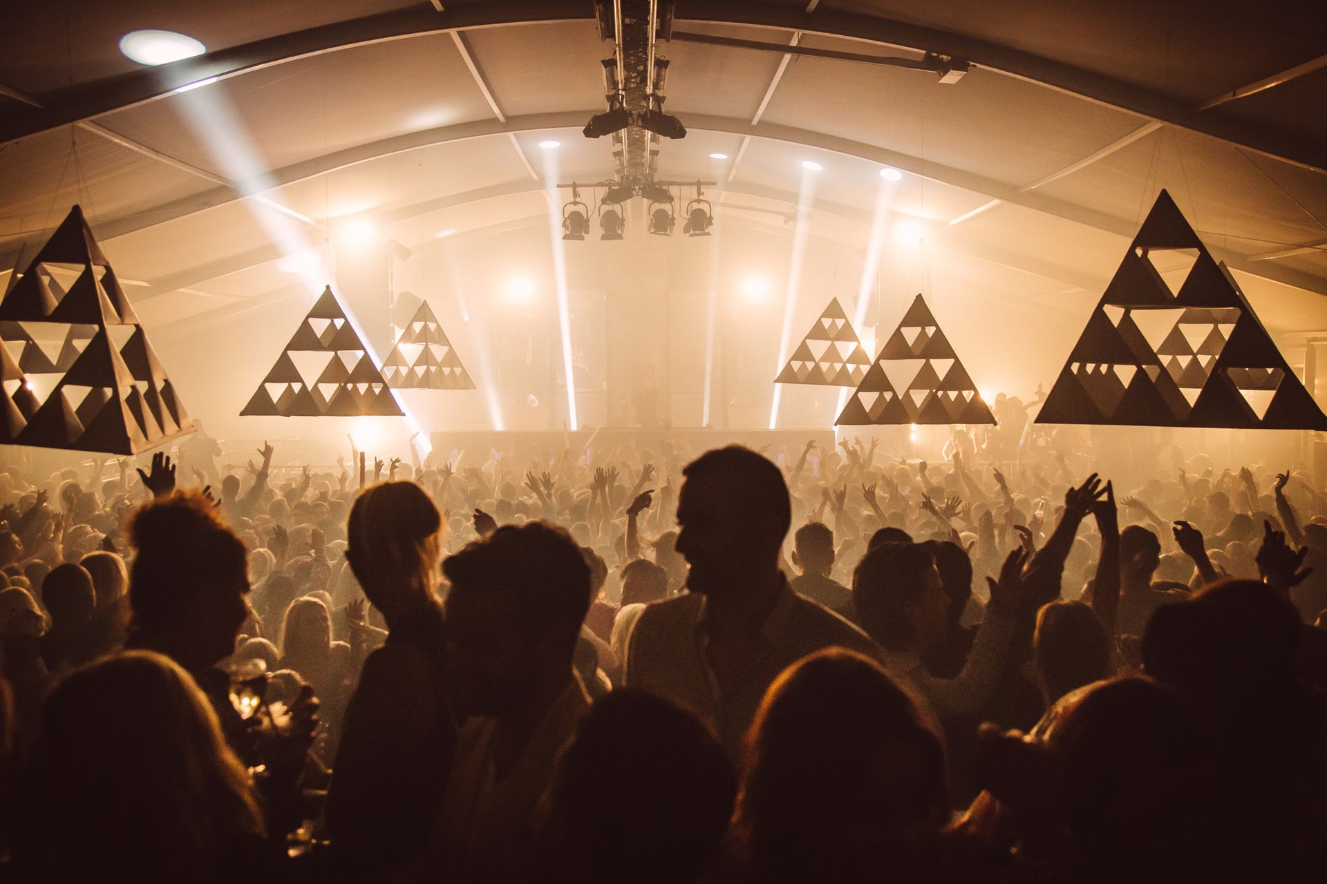 The dance floor of a dance club in Gothenburg is filled with people dancing and raising their hands into the air.