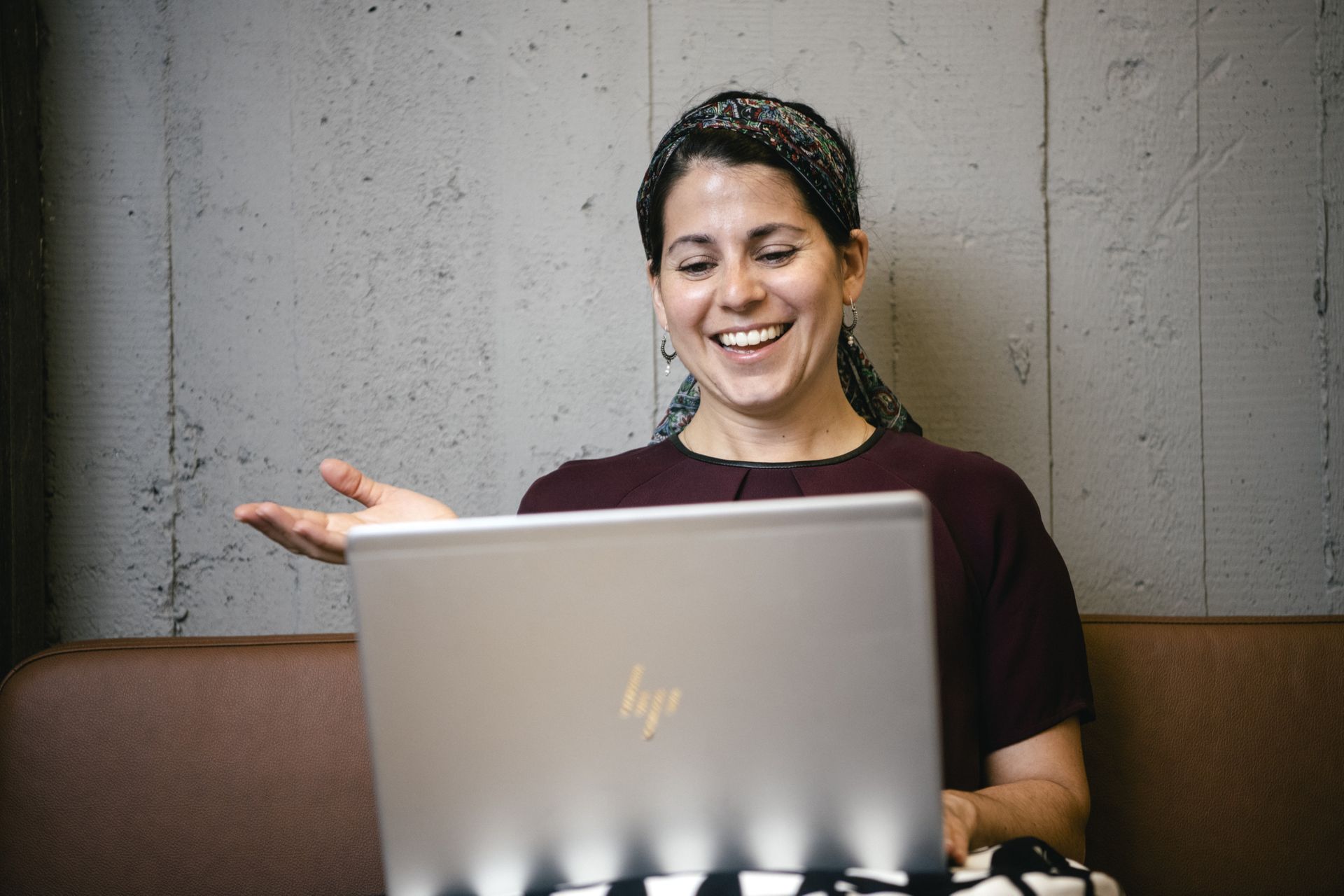 A woman sits with a computer in her lap. The woman is smiling.