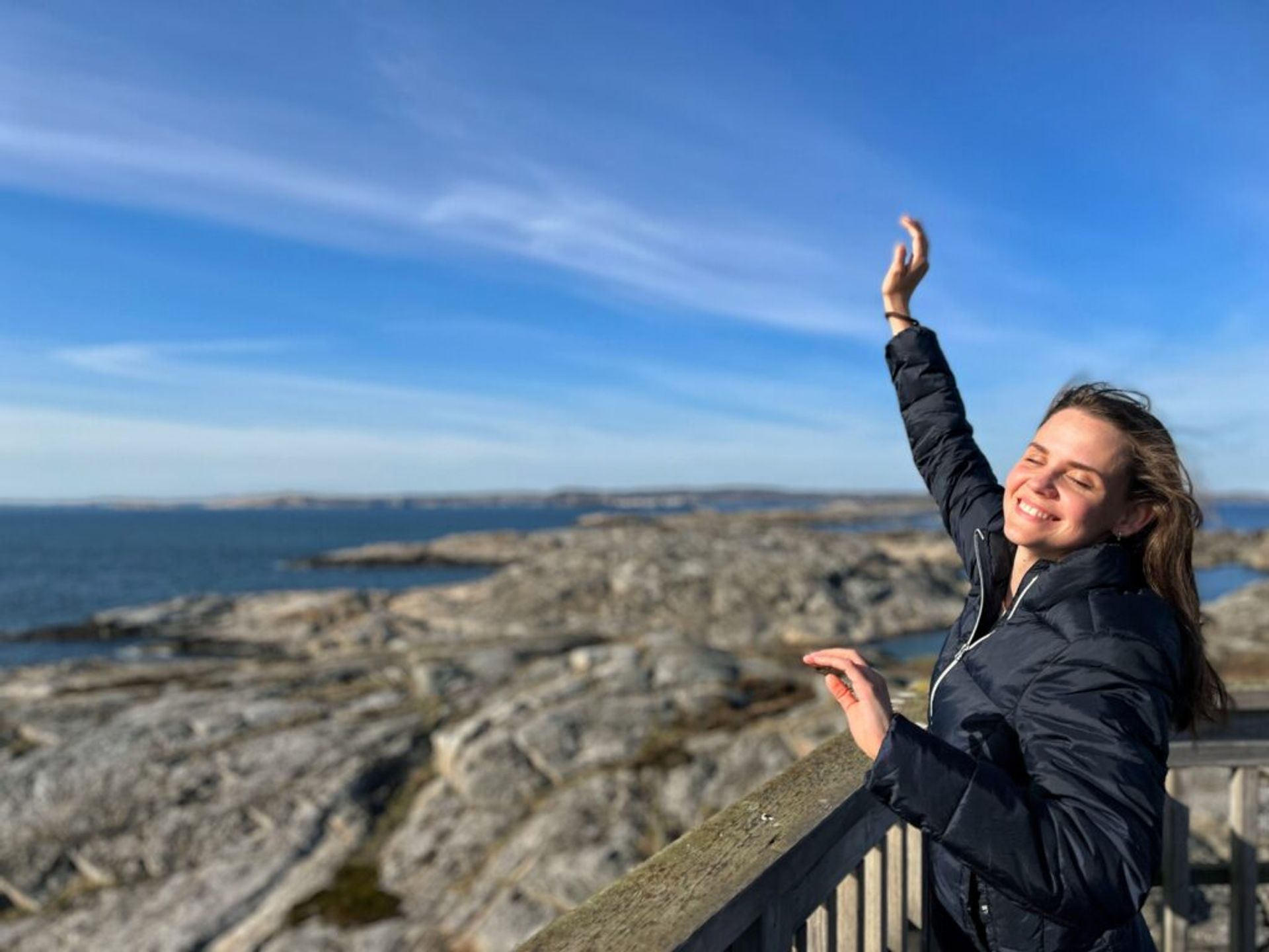 A woman smiles while being photographed against the backdrop of an archipelago.