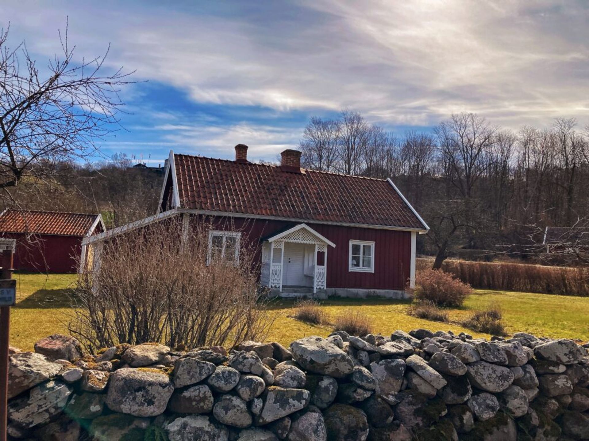 A classic Swedish red cottage, with barren trees in the background.