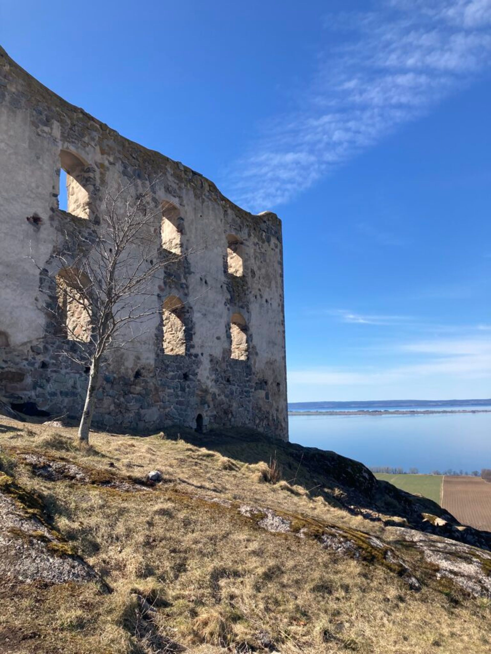 Stone ruins atop a hill with a lake in the background.