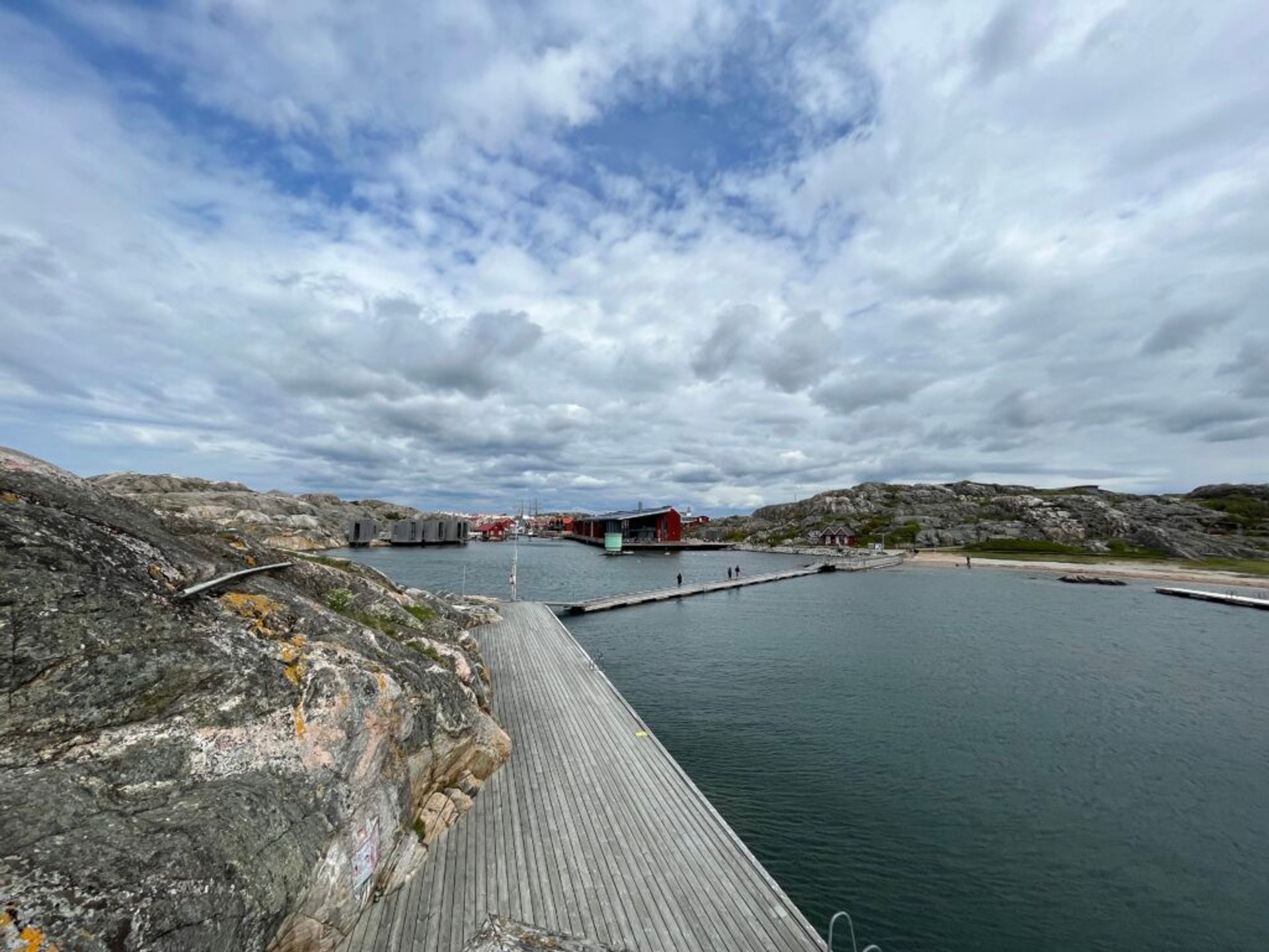 Panoramic scene of the western coast, showcasing a wooden boardwalk beside the ocean and rocky landscapes.