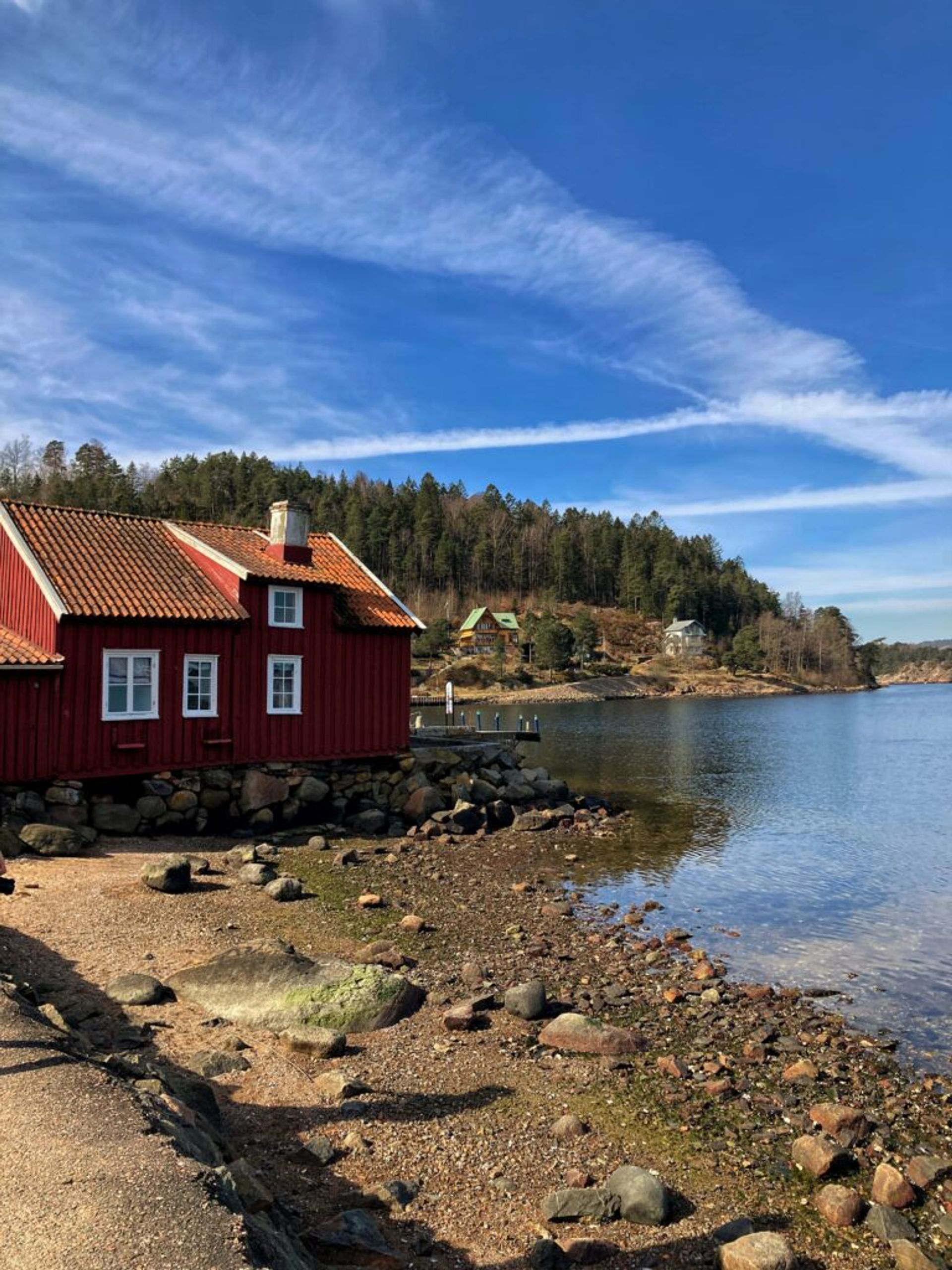 A picturesque coastal cabin with a backdrop of lush forest.