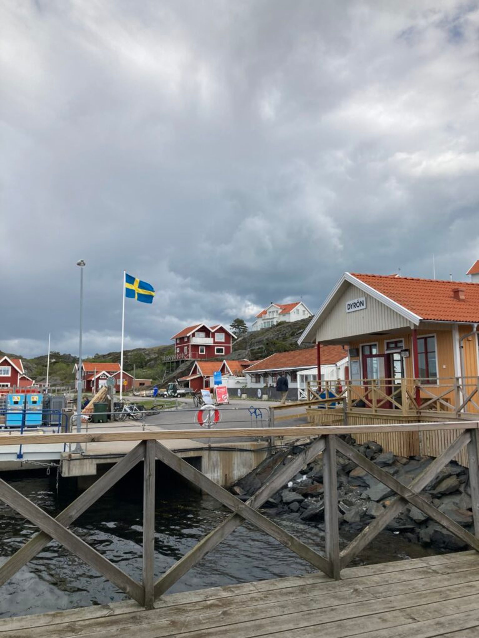 Traditional Swedish houses by a pier under a cloudy sky.