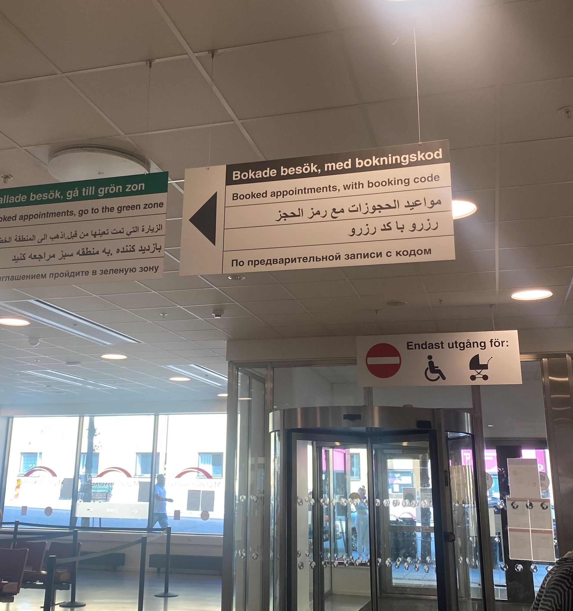 Interior of a Swedish Migration Agency office, showing directional signs guiding visitors to different areas within the office.