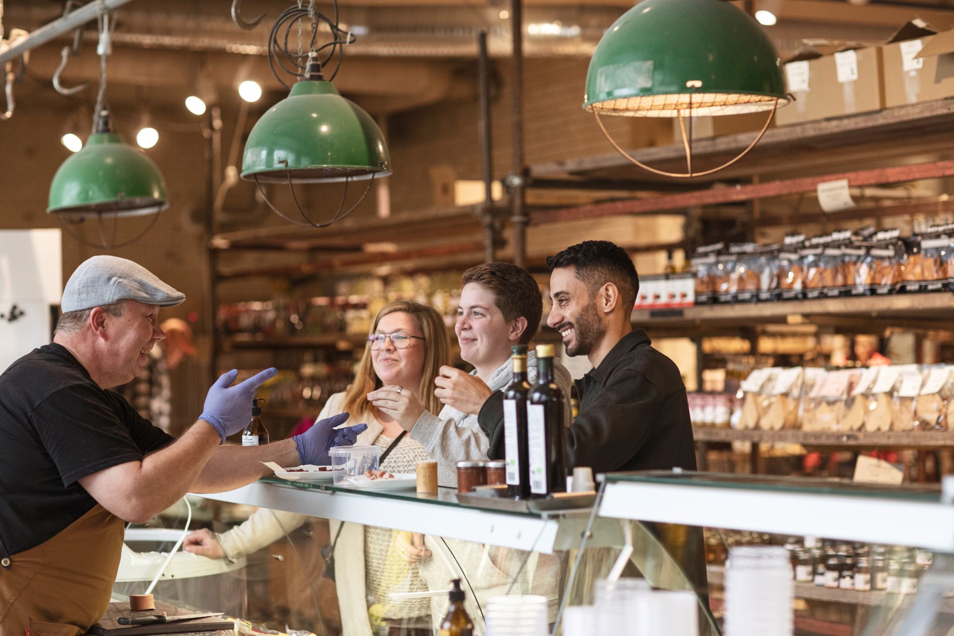 Three people are standing by a service counter in a food hall talking to a salesperson.