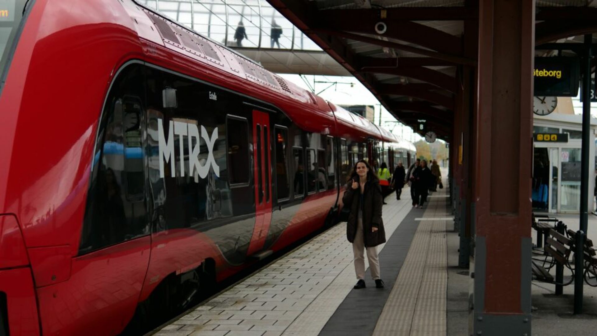 A girl taking a photo with incoming MTRX train. 