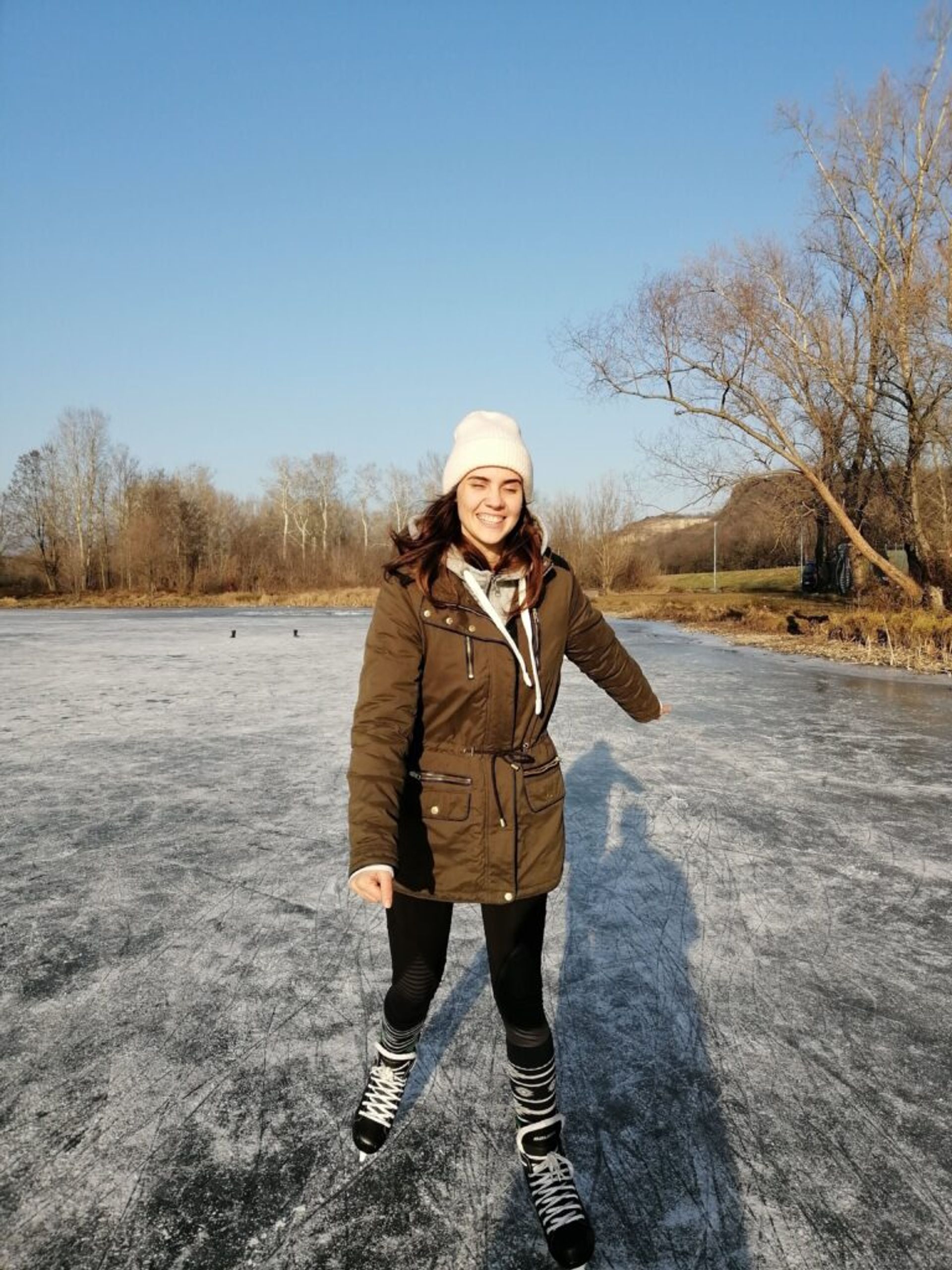 A woman smiles while ice-skating on a frozen lake.