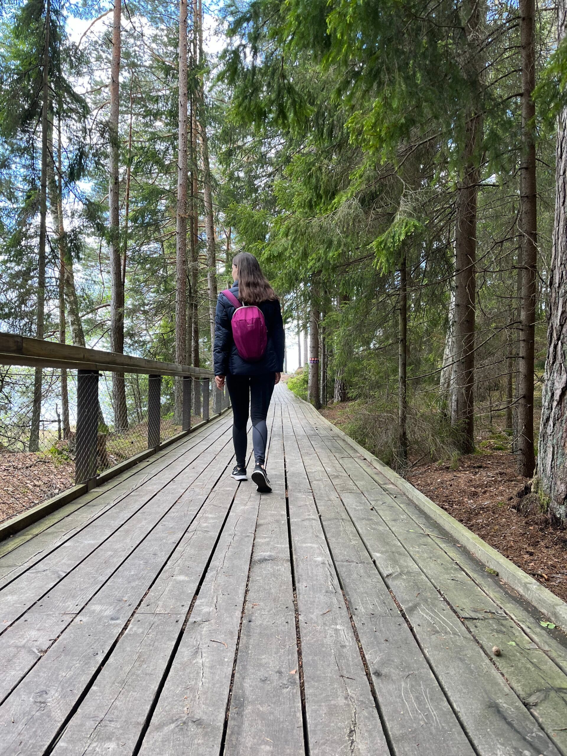 A girl walking on a wooden bridge in a forest.