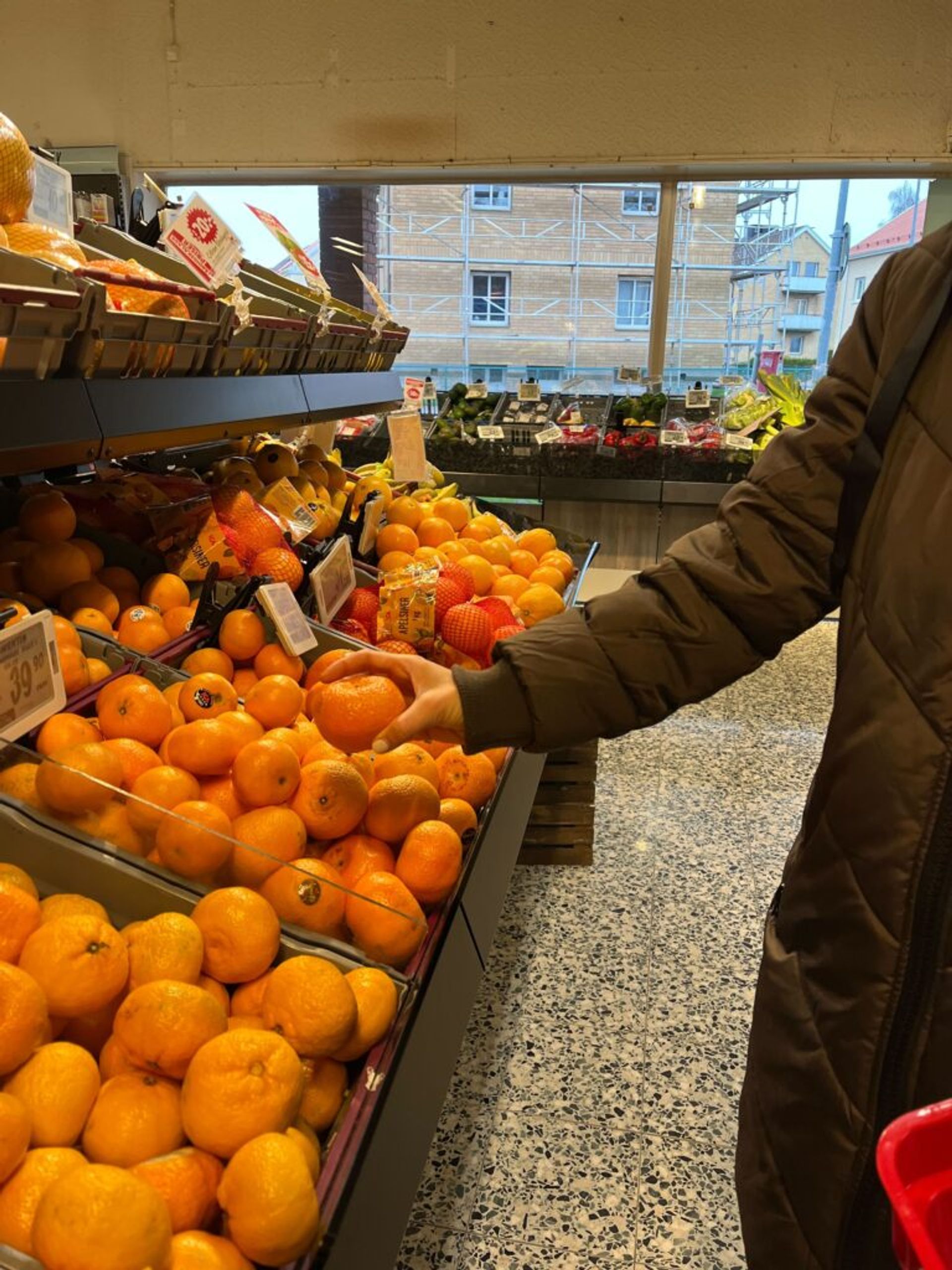 A person buying tangerines in a grocery store.