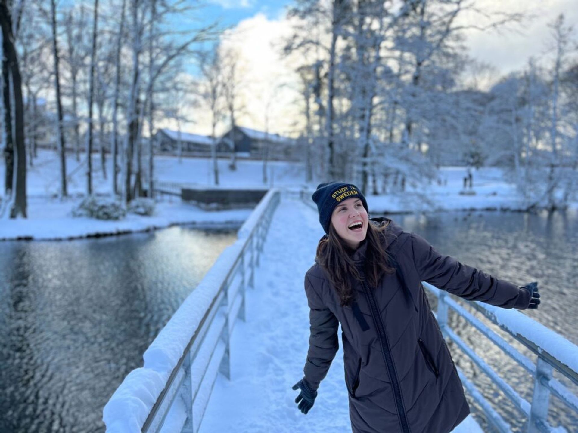 A girl laughing on a bridge covered with snow.