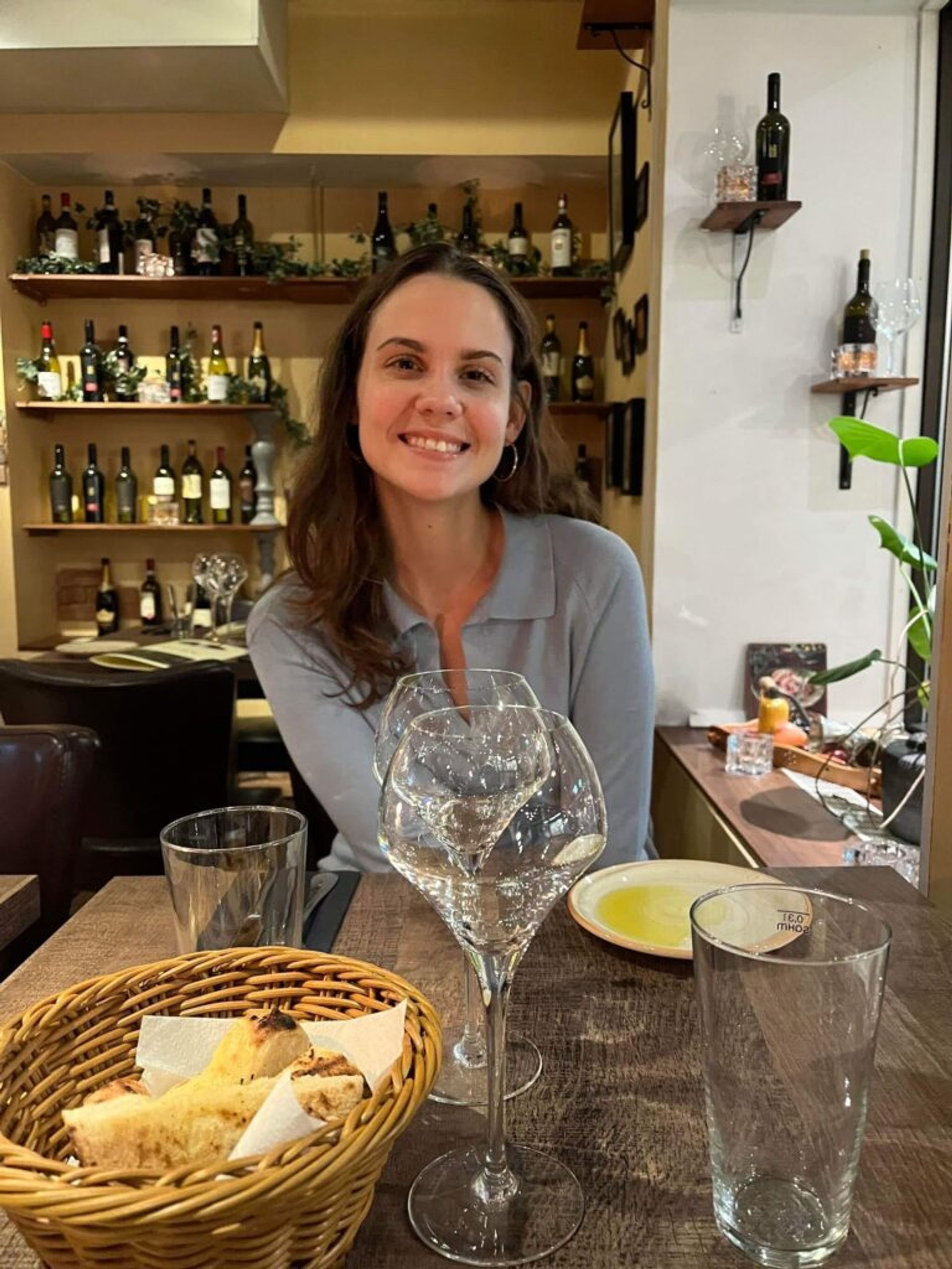 A woman smiles while sitting at a restaurant table. 