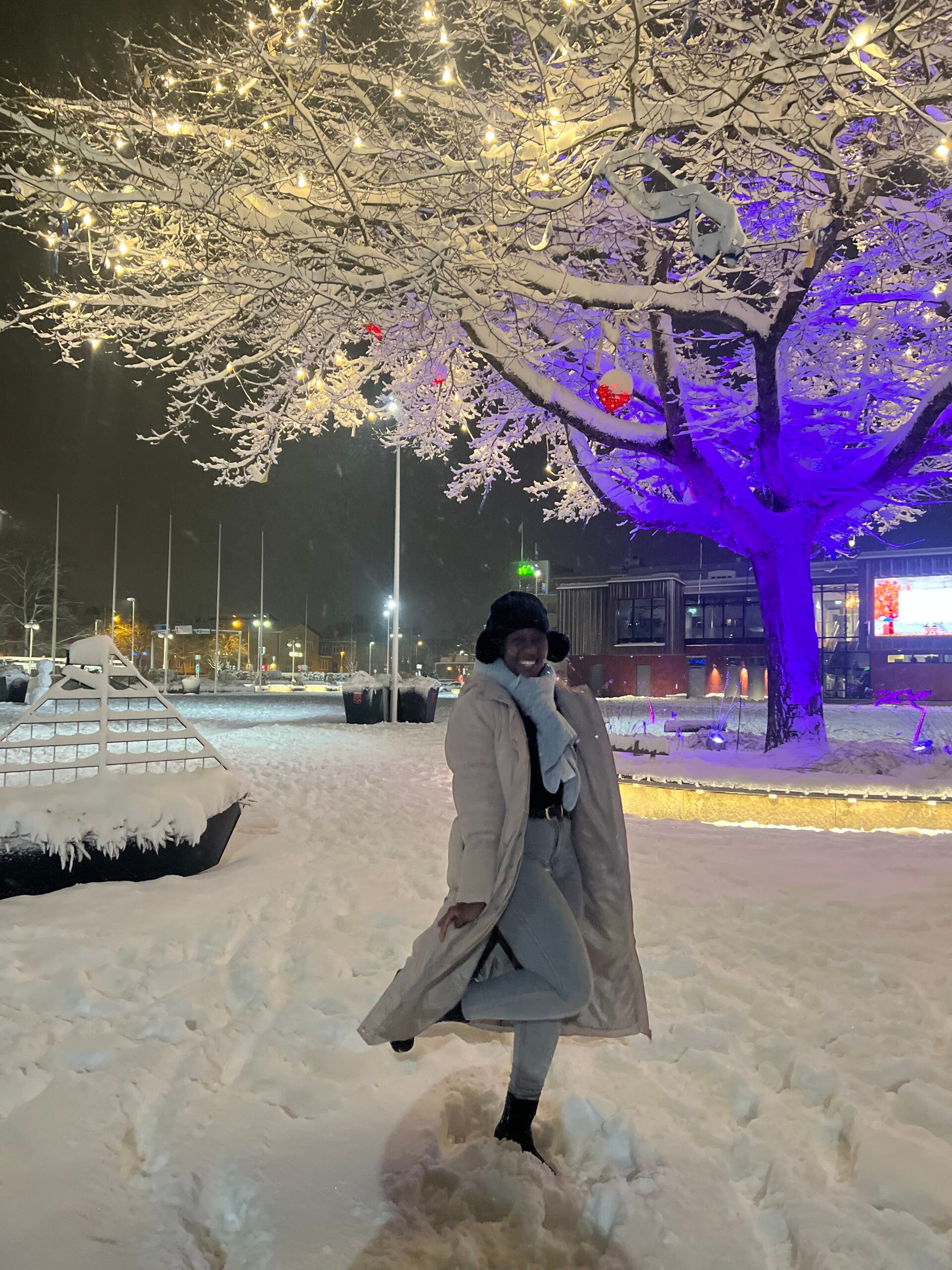 A woman cheerfully poses in the snow outside Oden Mall.