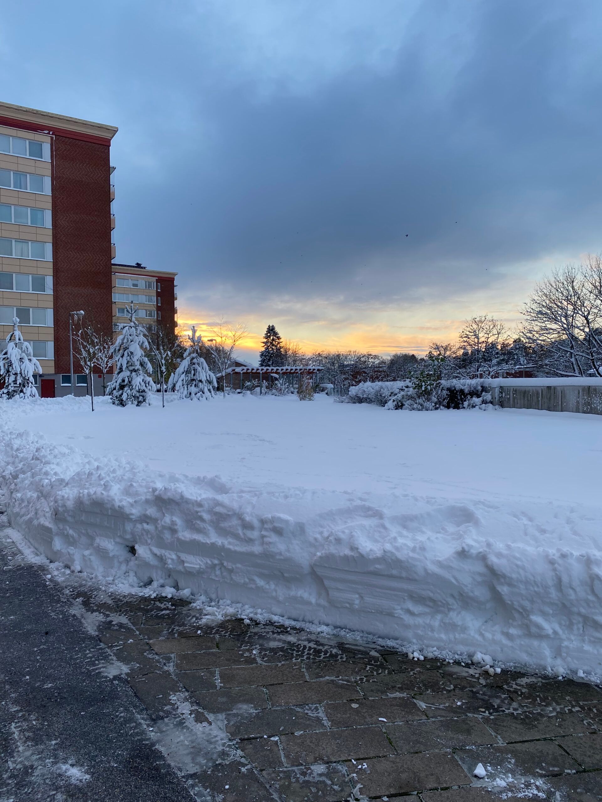 A snowy urban landscape with a large snowdrift in the foreground.