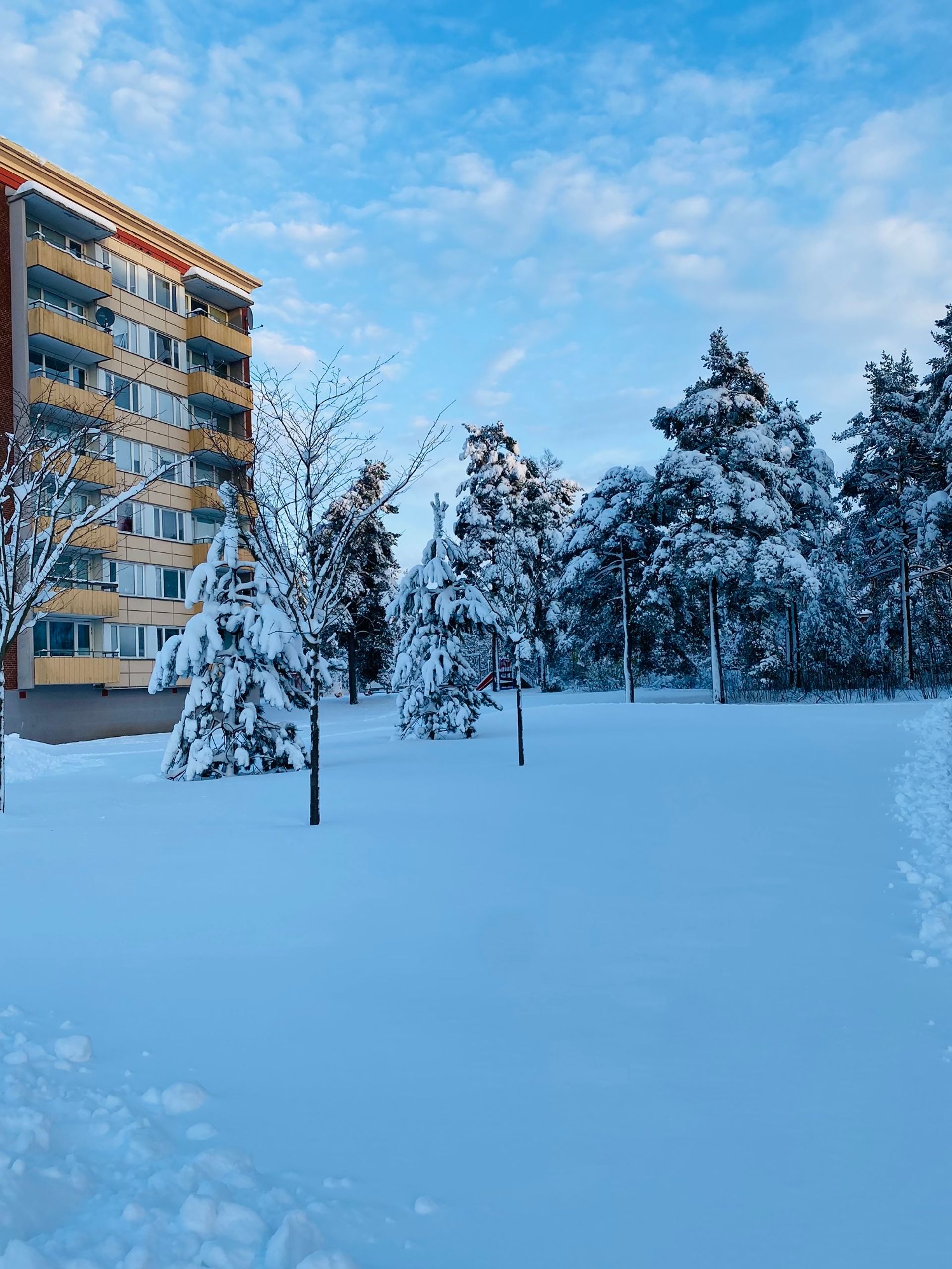 A winter scene featuring a multi-story building under a blue sky.