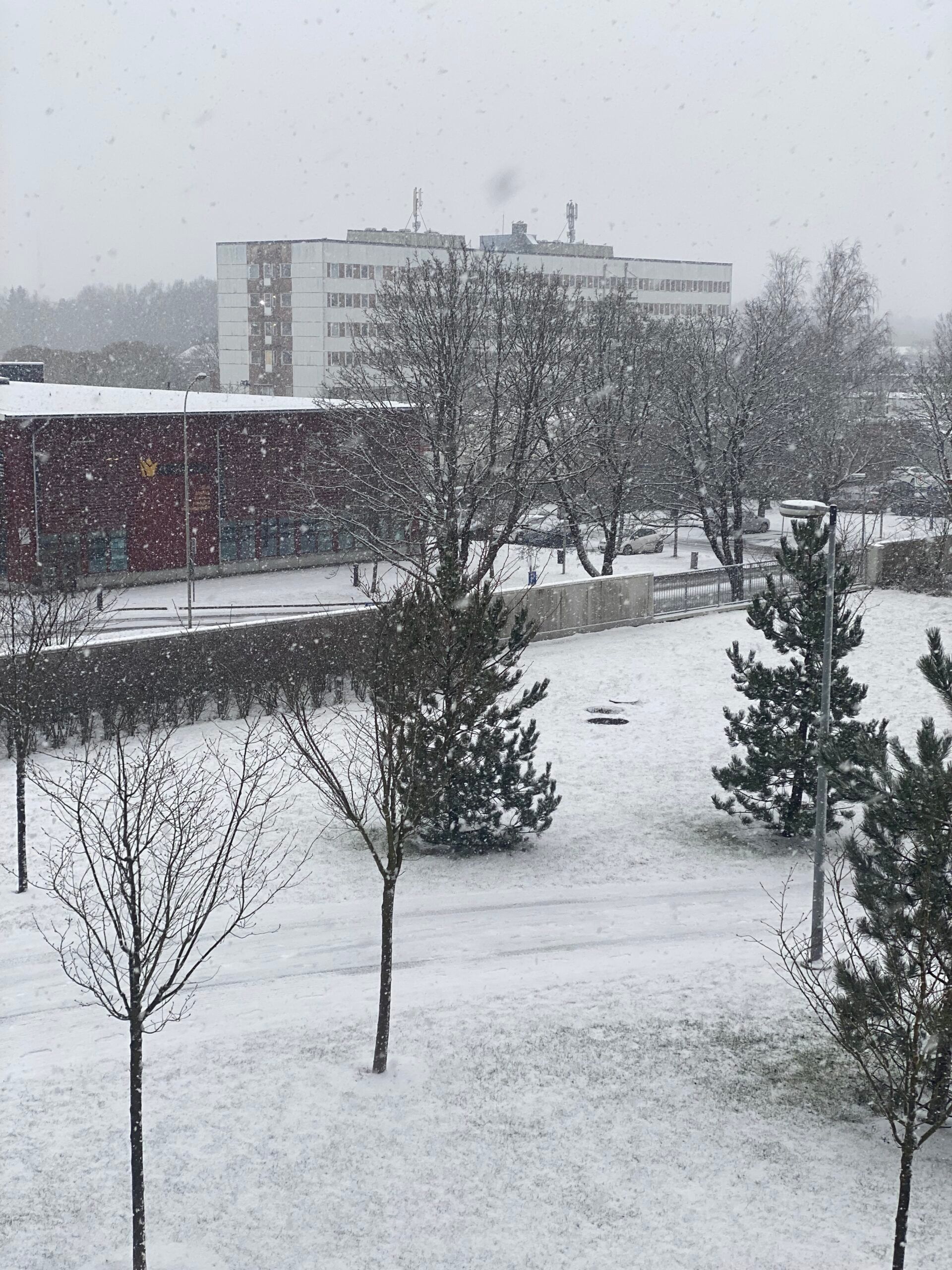 A winter scene of an urban setting seen from an apartment window.