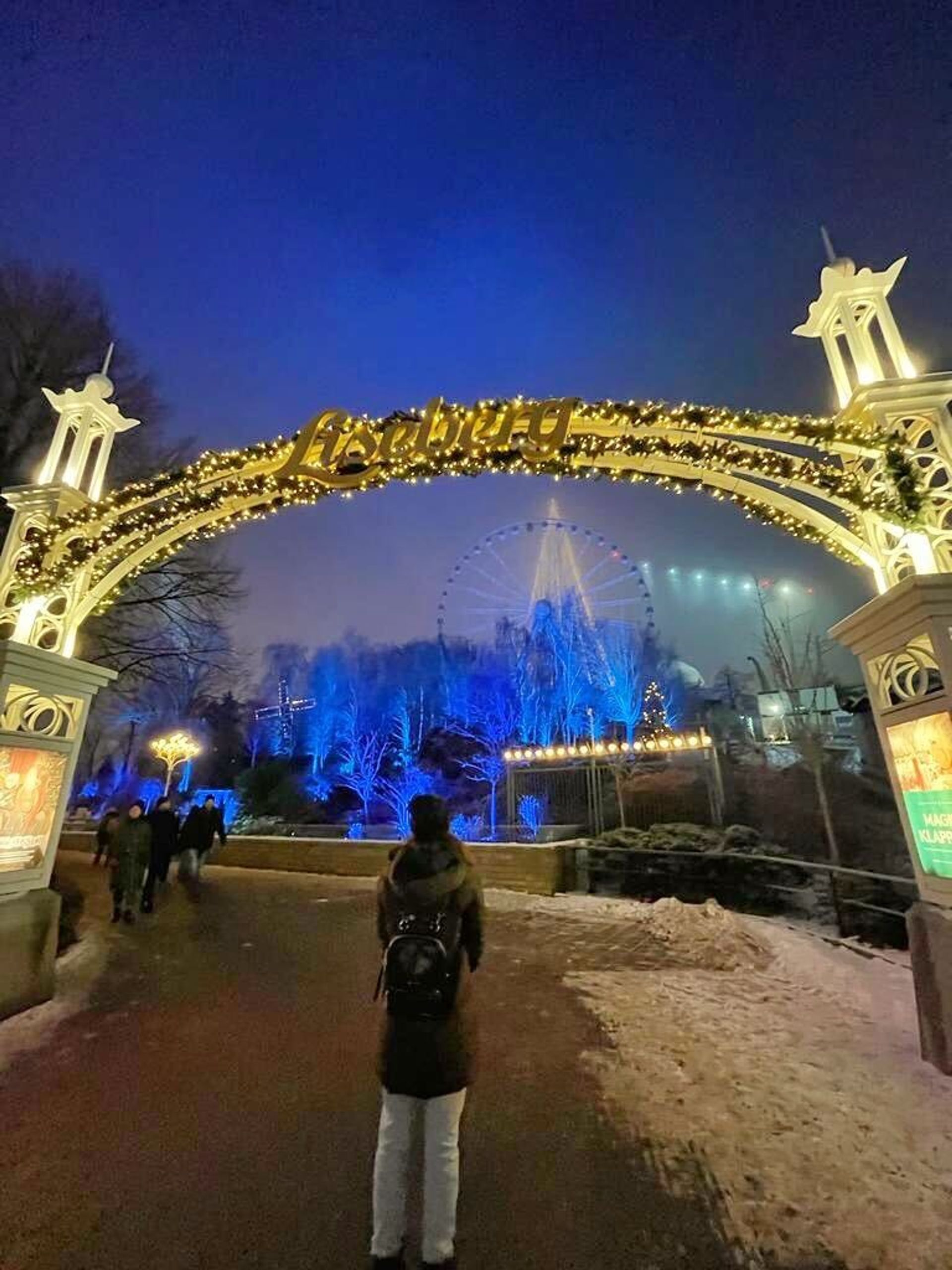 A girl standing under Liseberg sign.