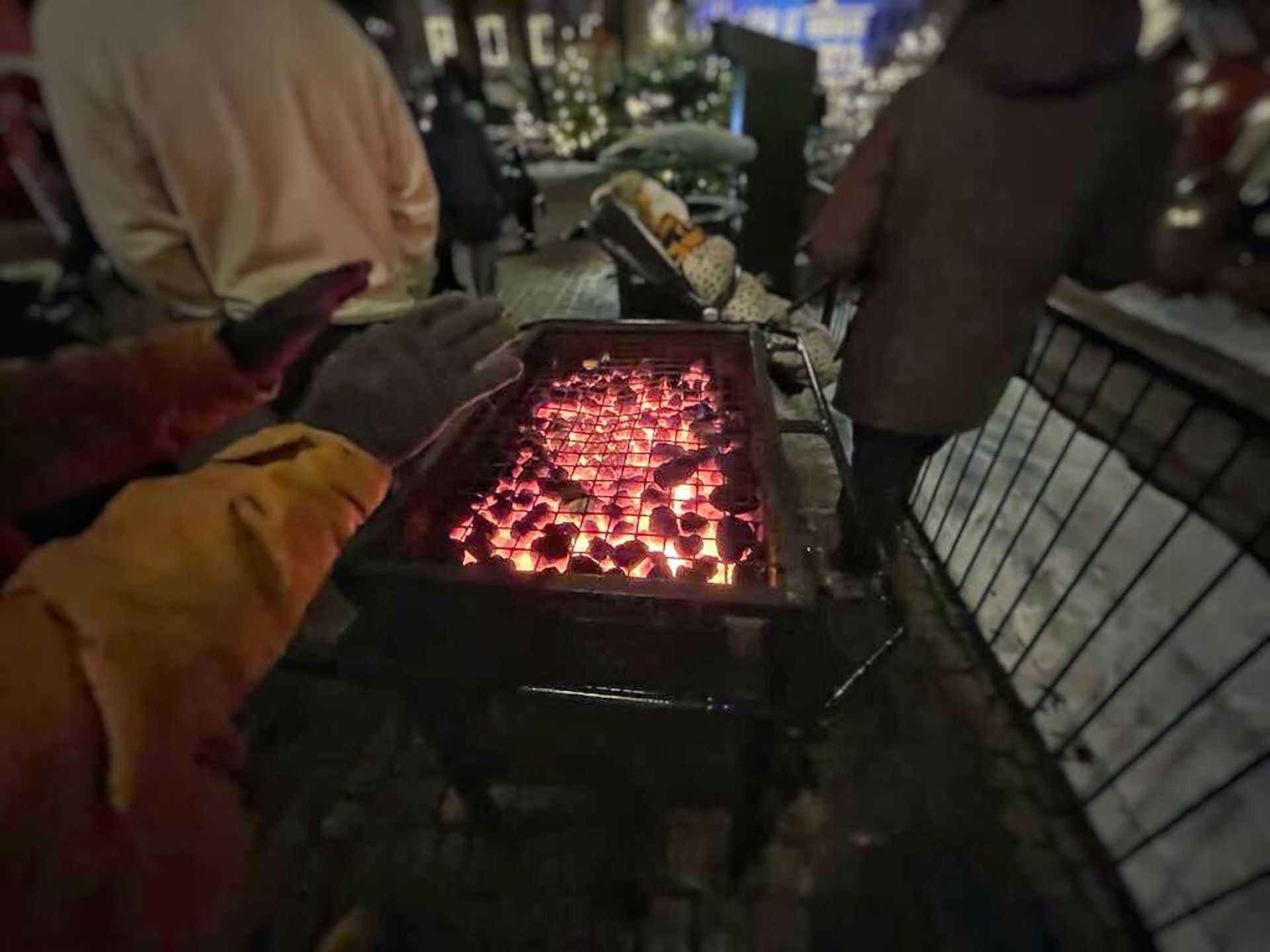 People gathered around a grill, drawn by the warmth of the glowing coals.