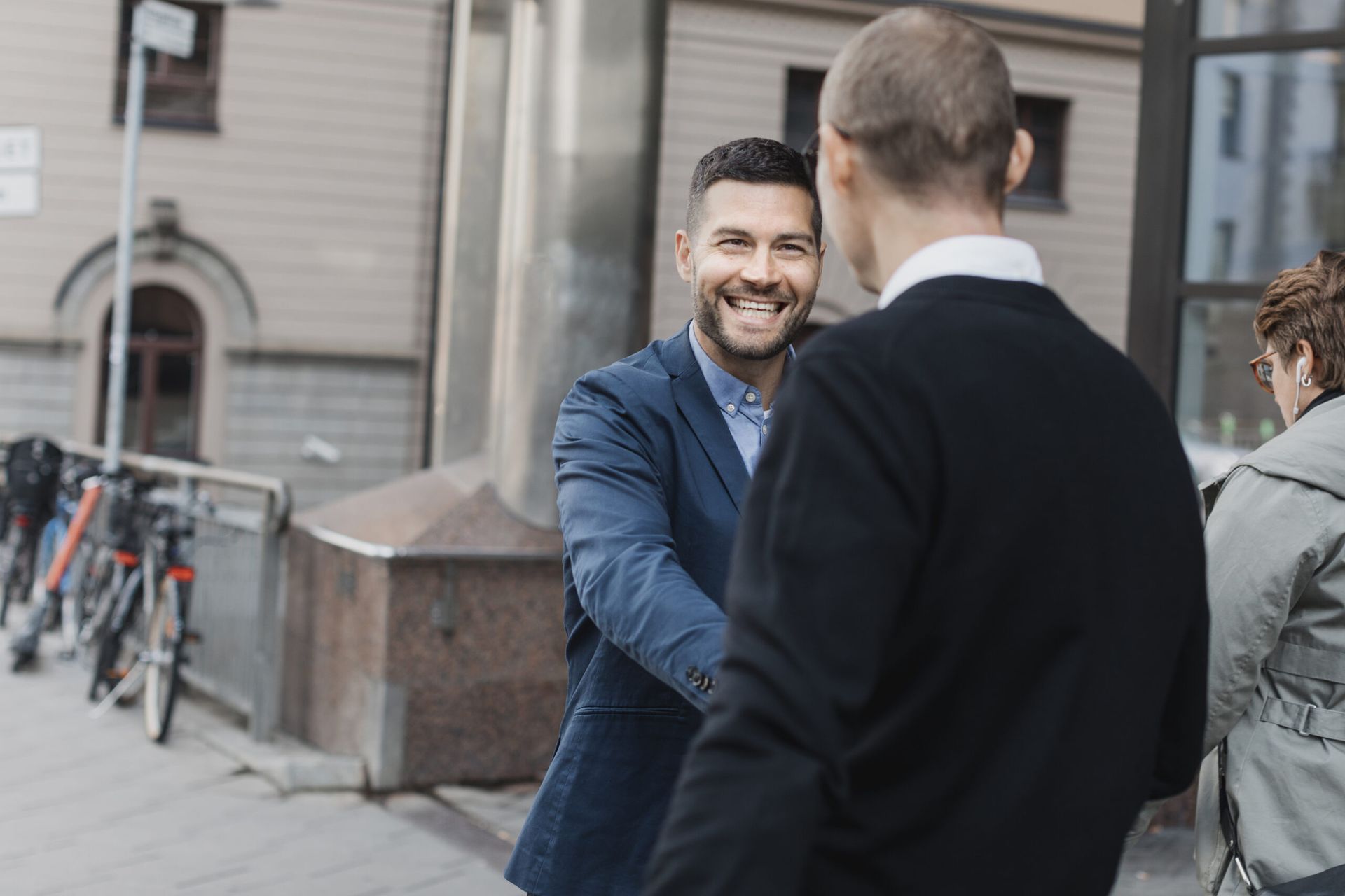 Two men warmly exchanging greetings with smiles on the street.